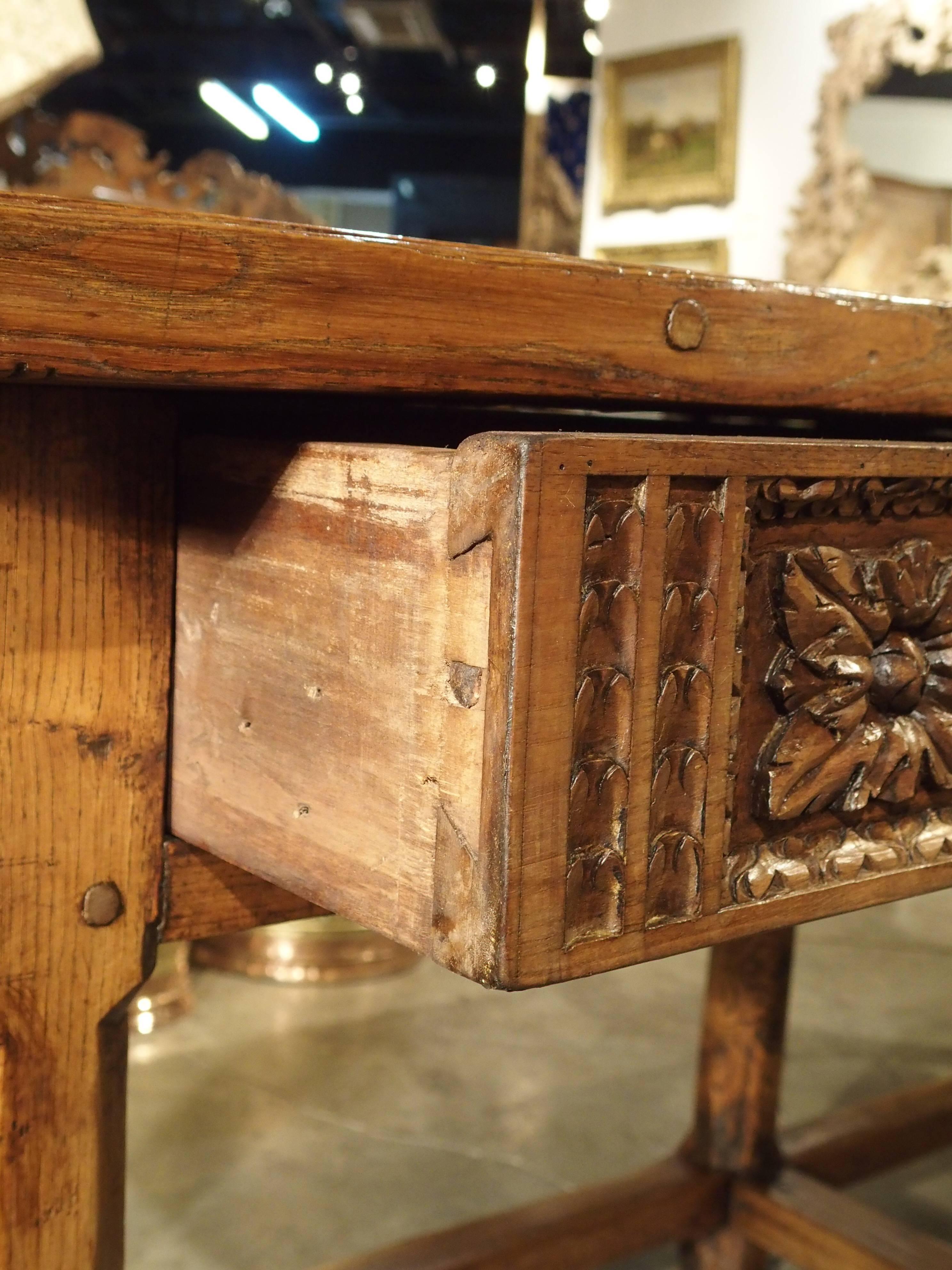 This stunning walnut wood and ash table is Spanish and dates to the 18th century. It is carved on both sides so it could easily stand in the center of a room. The rectangular top rests upon two hand-carved drawers on either side with original drop