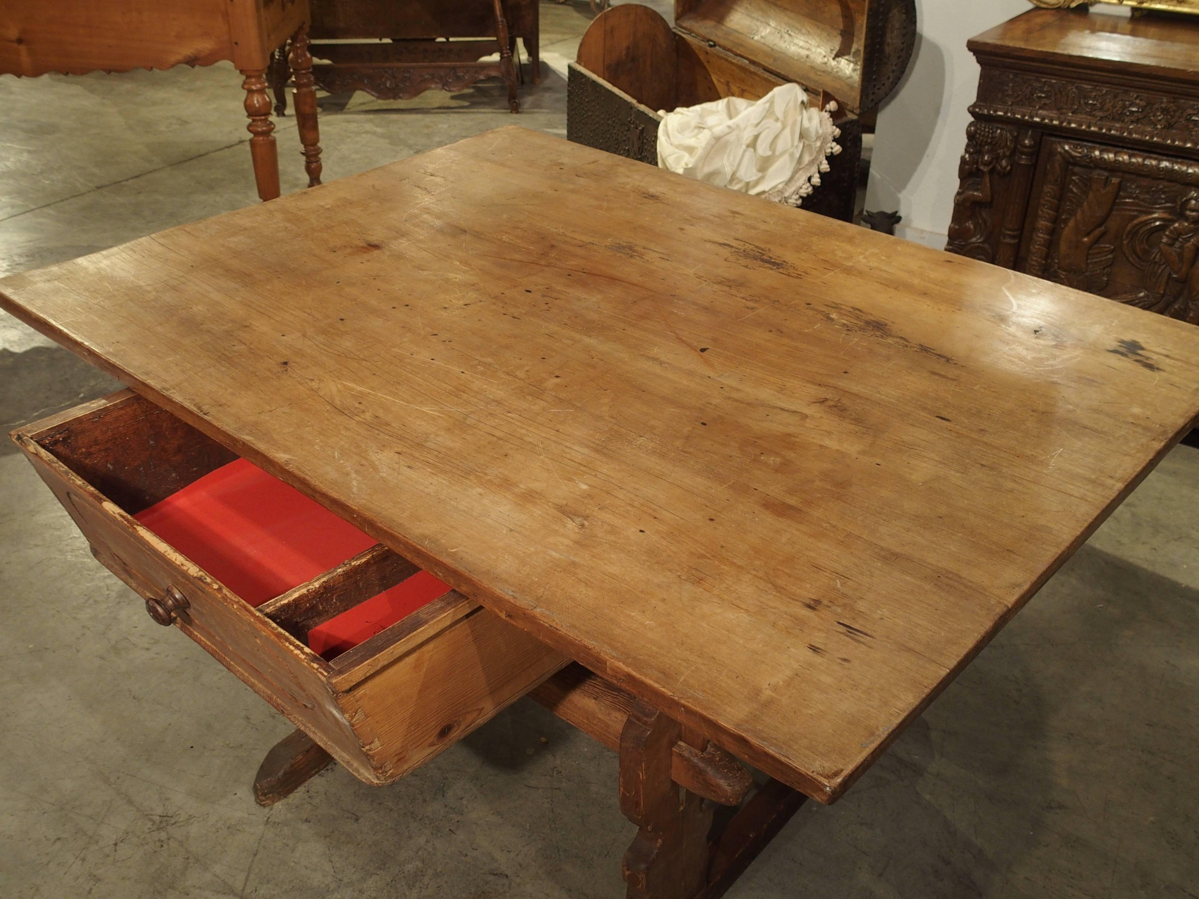This quaint mountain table is of Savoie or Swiss origin and is made from softwood pine and fruitwood. Its top is sizeable at 31 x 51 while its base is smaller. This allows for leg room and more seating at the table. The apron has a drawer for