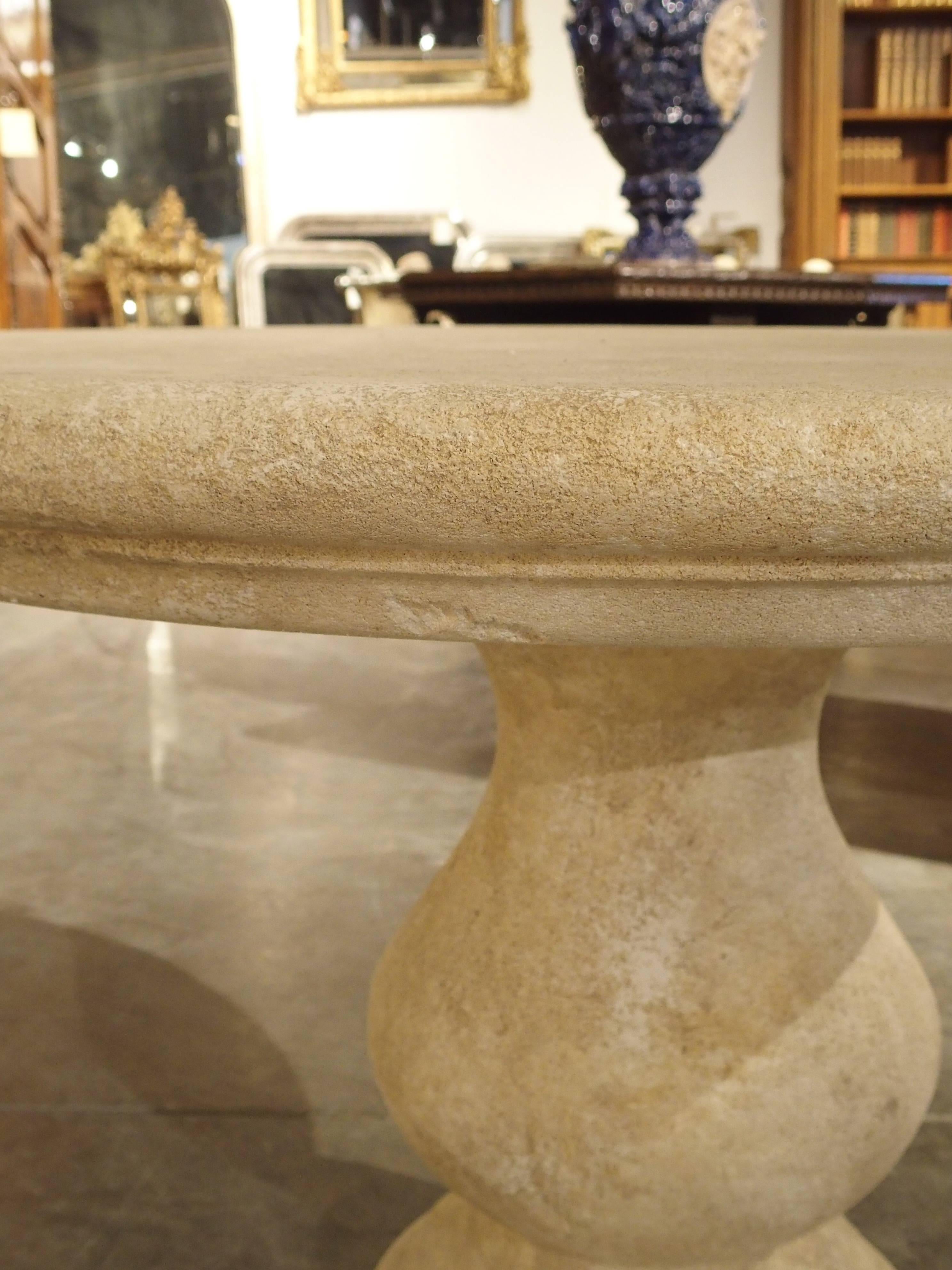 This versatile, hand-carved, round stone table from France can be used outside as well as inside. It is made of French estaillade limestone, which has been used for centuries in the creation of outdoor pieces. The rounded edge top sits on a large,