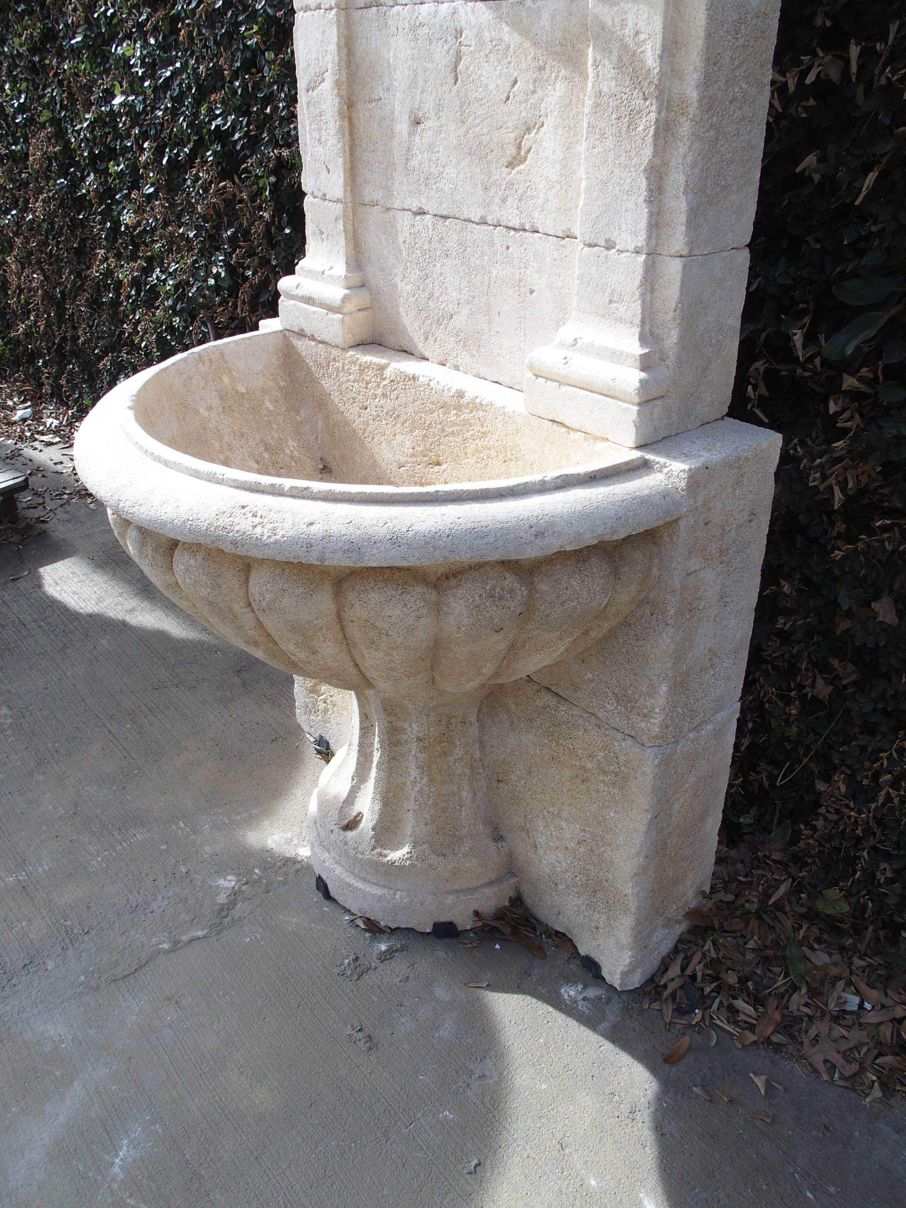 This stunning, hand-carved wall fountain from France has been designed with architectural ornamentation. There is a crown molding with pilaster capitals and pilasters on either side ending in a plinth at the lobed basin. It is handmade from