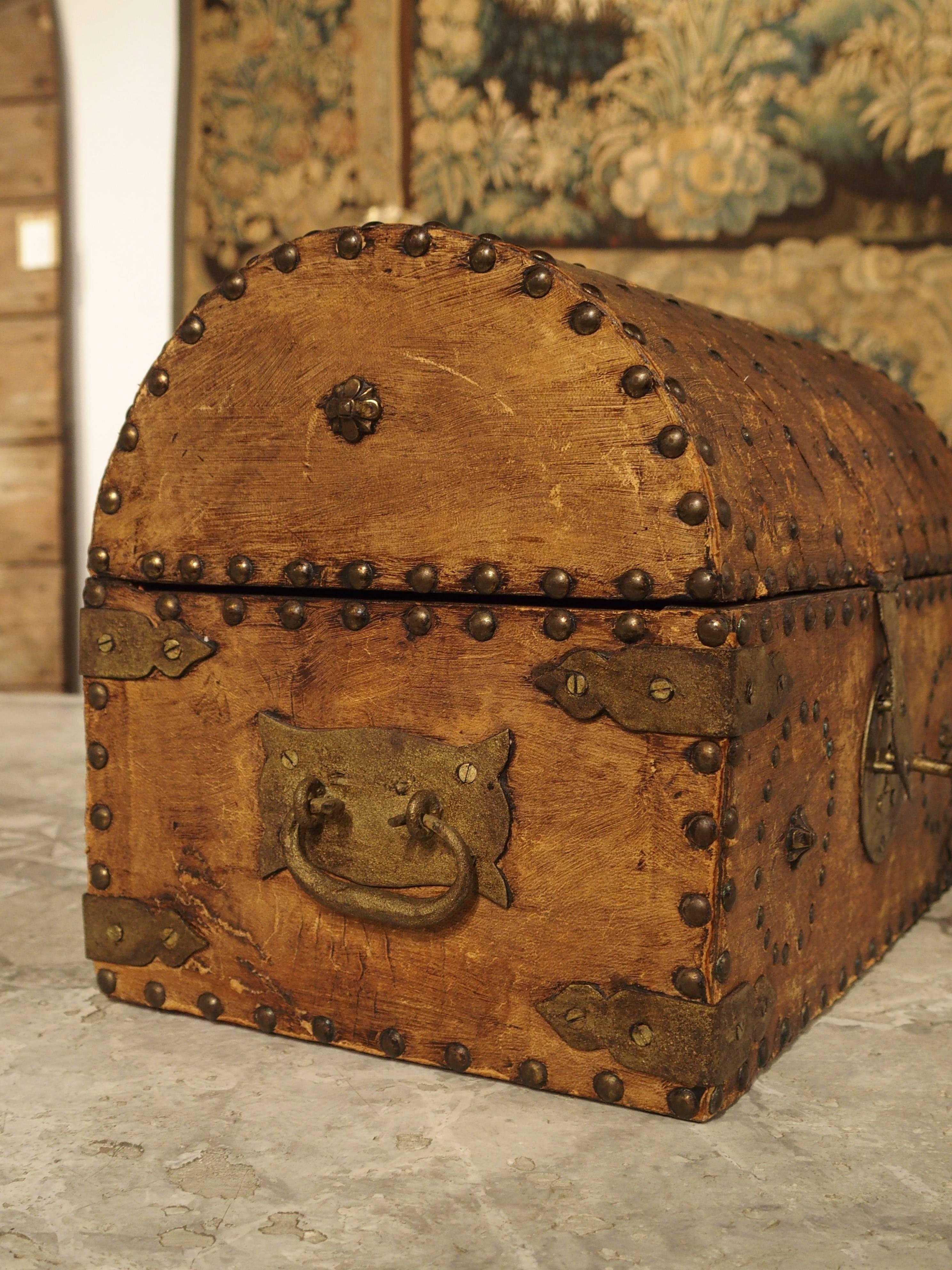 This decorative tabletop trunk is from Europe and dates to the end of the 19th century. It has diagonal, patterned ground motifs on its domed top. Small stamped florets are at each centre surrounded by tiny nailheads. The front of the trunk is