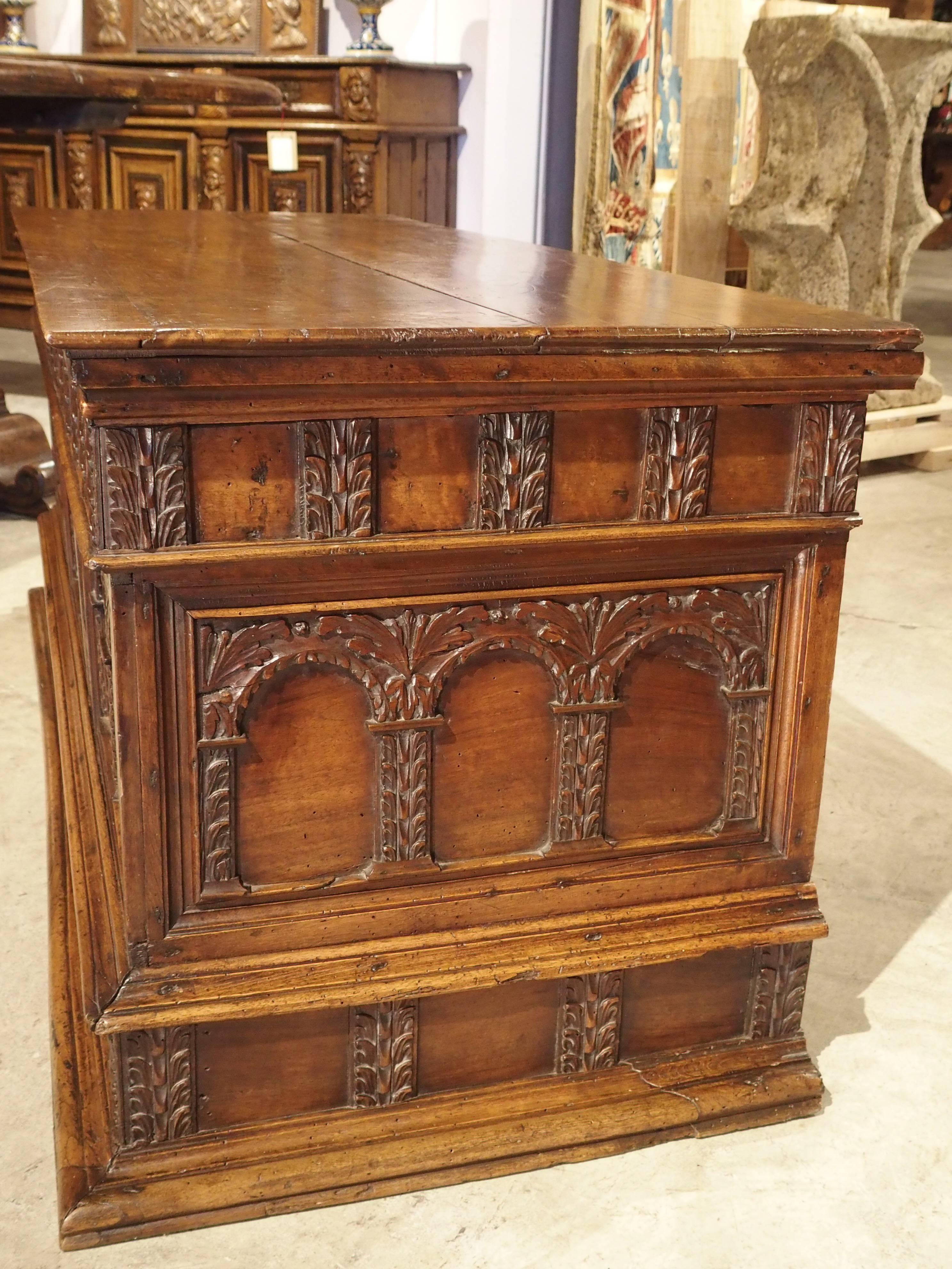 This elegant 18th century walnut wood Italian trunk is in the early Renaissance style. It's predominant motif is multiple architectural arcading. Other motifs are foliate in nature throughout the trunk. There is a wonderful, unusual detail which is