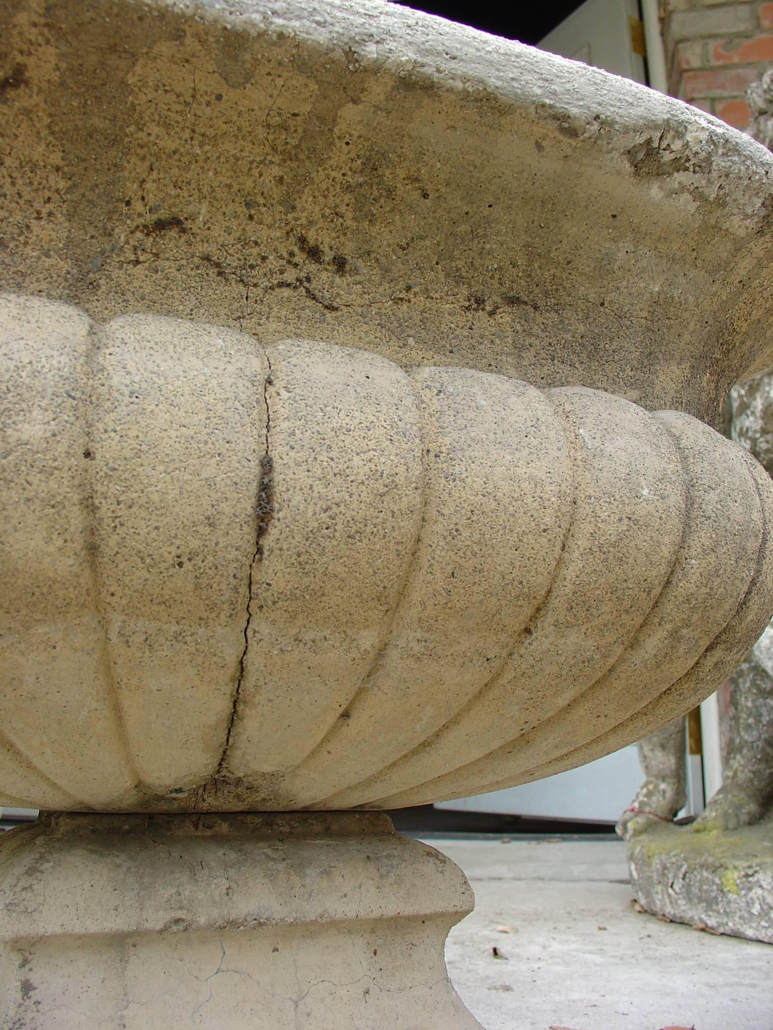 This is an antique reconstituted (cast) stone urn from early 1900s France. The material is a mix of crushed stones. The attractive shape is simple and Classic, and the planter is comprised of two sections (bowl sits on base).