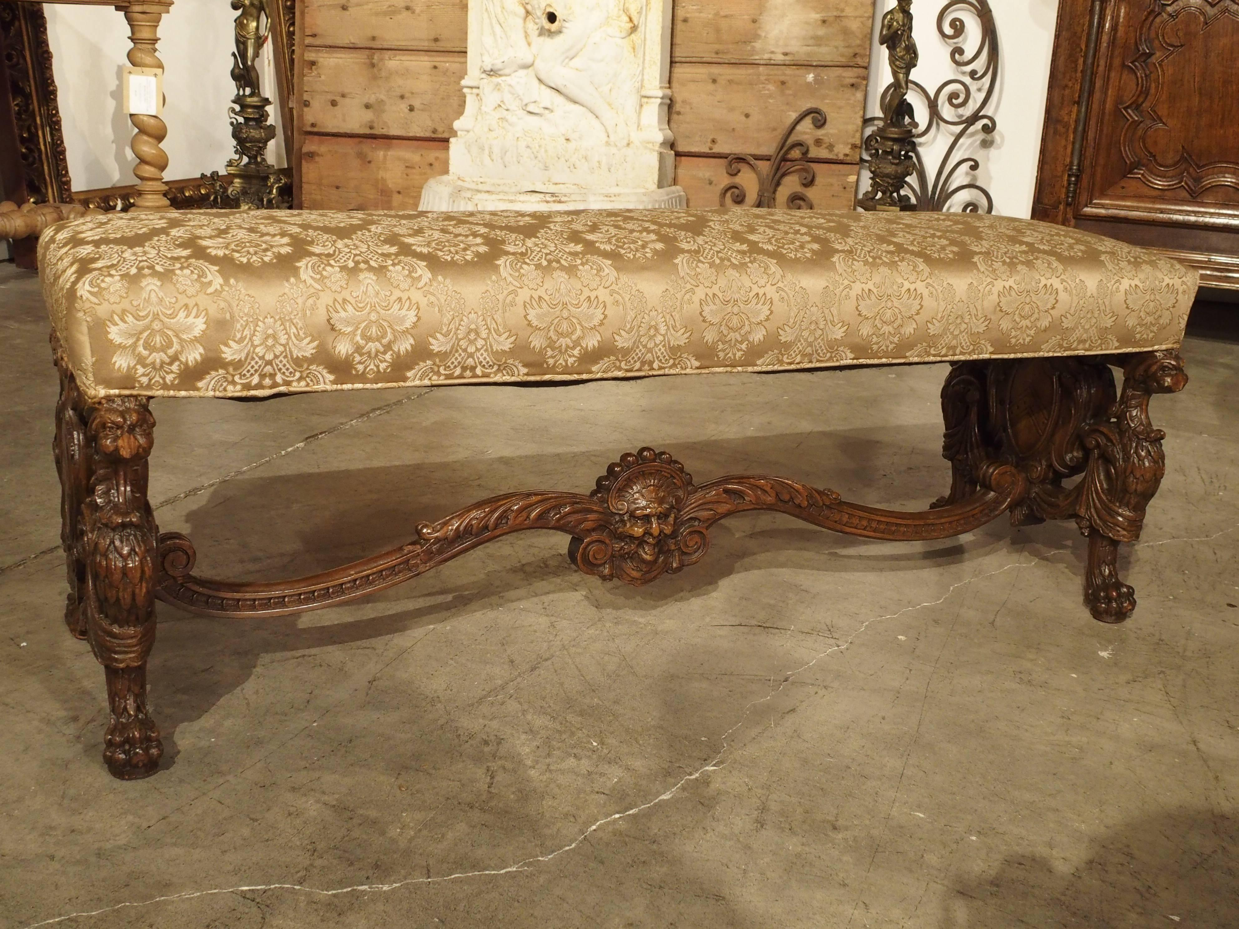 This is a beautifully carved walnut wood Italian bench with padded silk patterned fabric. It dates to the 19th century and most recently belonged to Warner Brothers Studio collection in California. The carving is meticulous with the benches’ legs