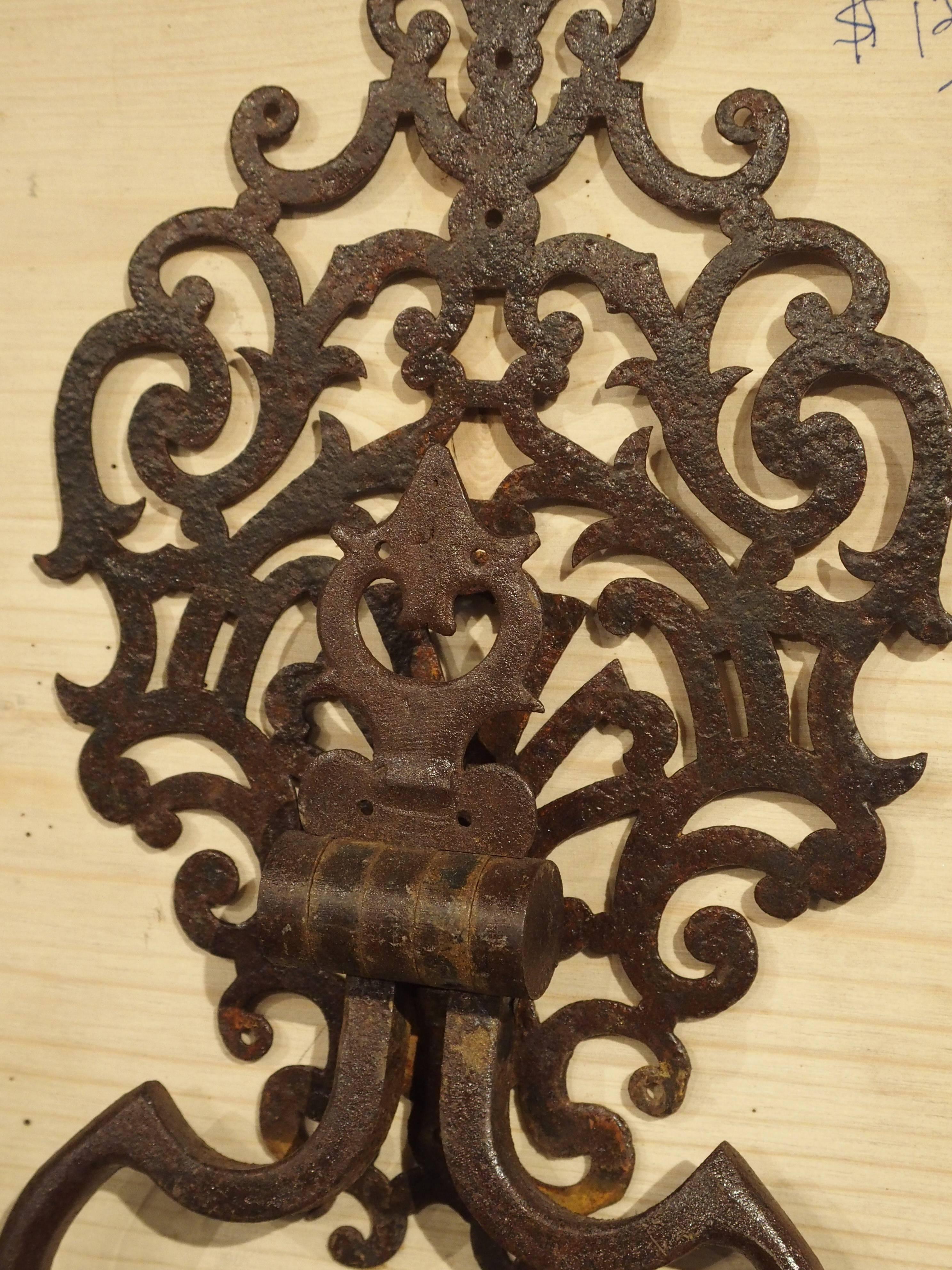 This iron door knocker is modeled from an 18th century door knocker found on a door at a chateau in the Luberon area of Provence France. This particular one has a multitude of pierced scrolls within an elongated oval shape. The door knocker itself
