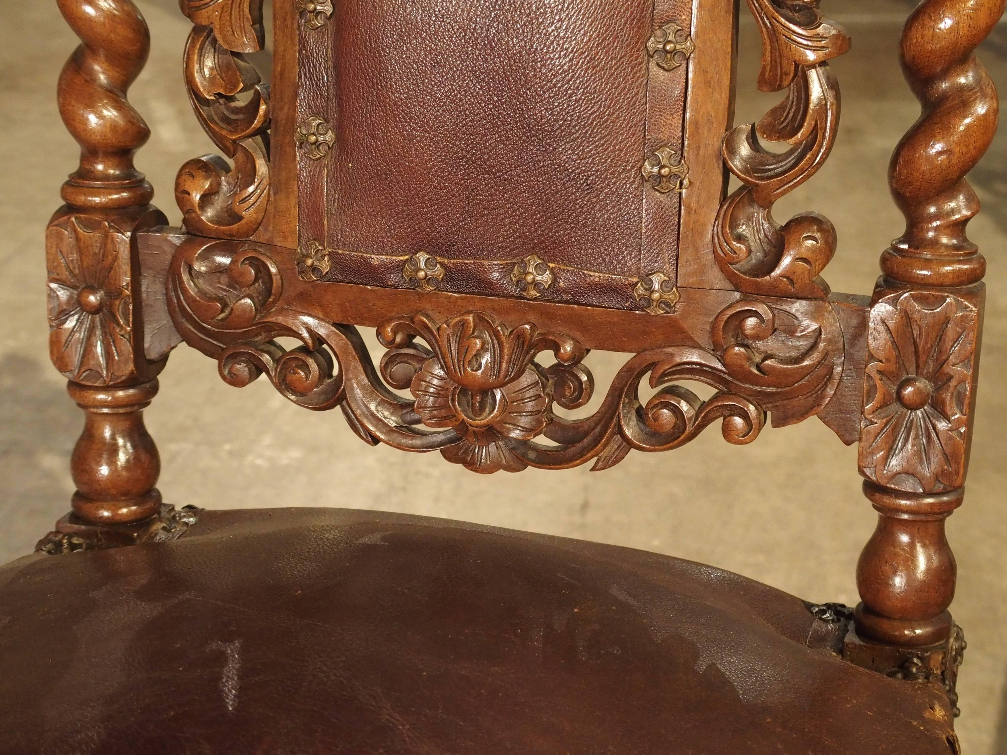 These beautifully carved antique walnut wood French dining room side chairs date, circa 1880. They are covered in soft brown leather, which is affixed with nailheads in the shape of a Maltese Cross. There are a myriad of floral, foliate and fruit