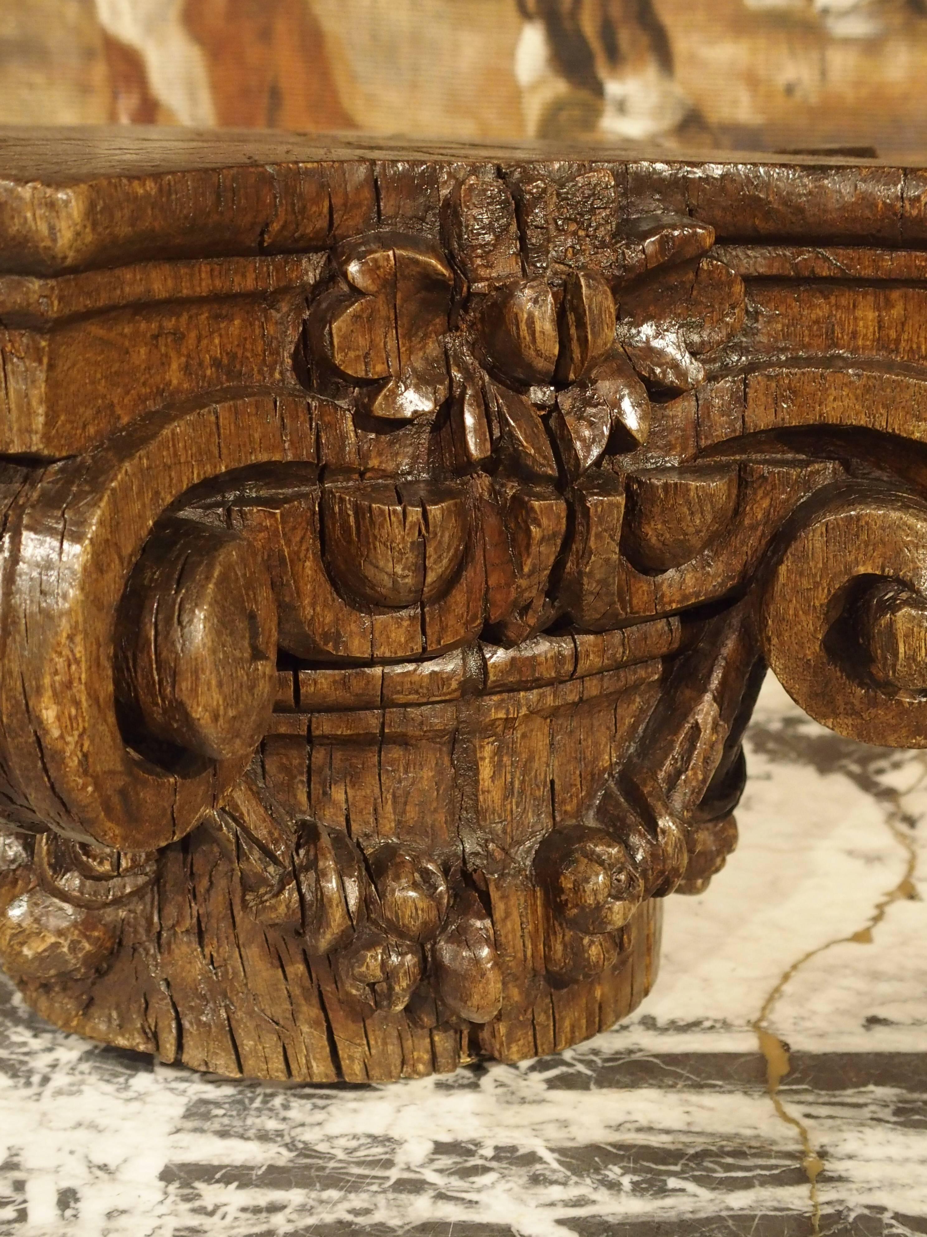 This French, hand-carved Ionic capital has been carved out of European Oak. The motifs are single flowers at the top center, stylized egg and flower, with garlands of fruit hanging from the scrolls on either side. This ornamentation is on three