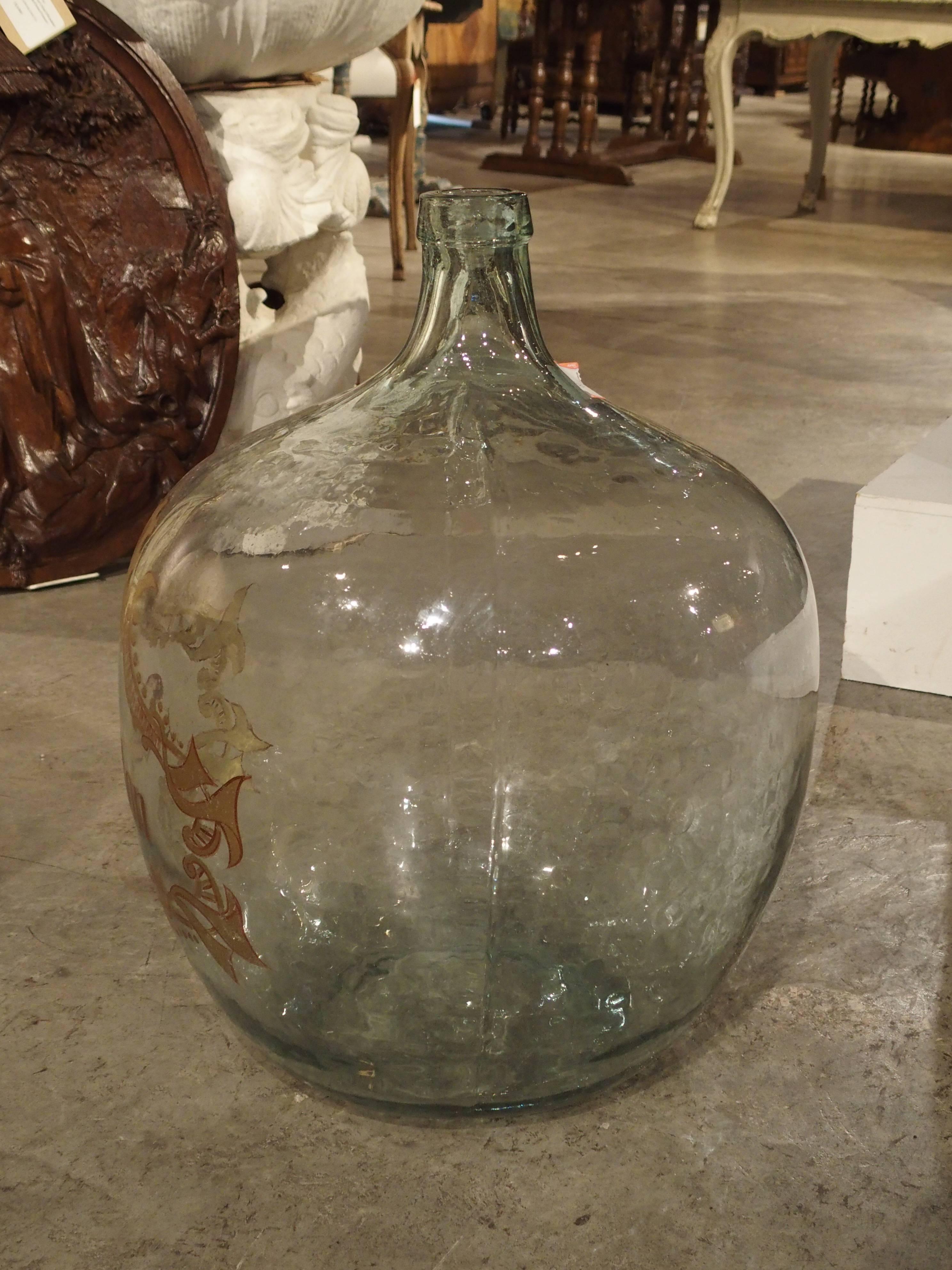 Demijohn bottles are used for storing wine and spirits and have been in existence throughout the world for over 300 years. This bottle has been handblown and hand-painted in gold outlined in a garnet color. Today, they be used as decorative