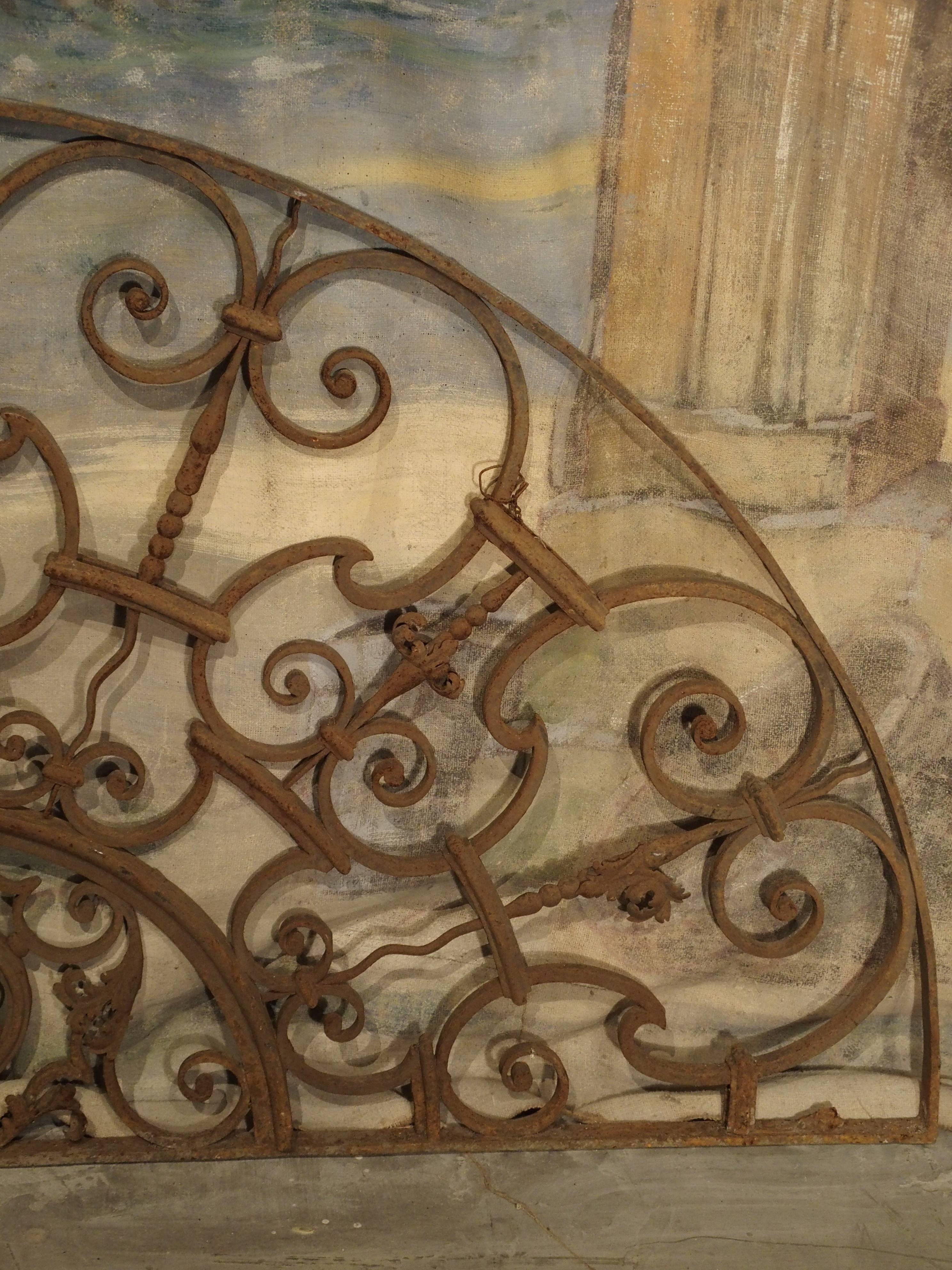 From Provence, this graceful, scrolling iron, transom/overdoor gate is in the shape of a demilune. At the bottom is another demilune with a cartouche featuring more C-scrolls and a triangle outline. These gates were originally used in different