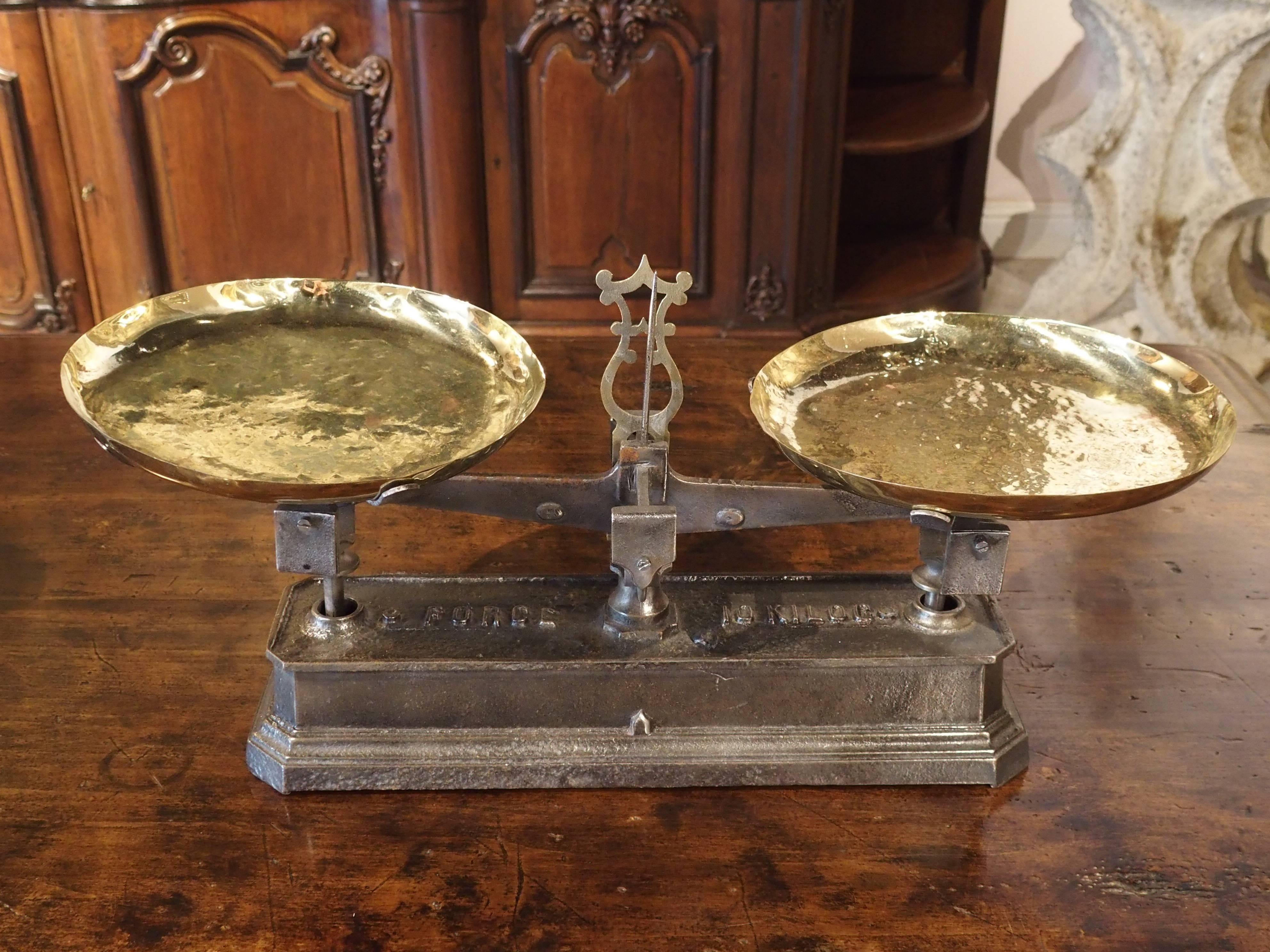 French scales of this type were used in stores for weighing produce. They consisted of a cast iron base with the weight mechanism at the top center. The arrow would have to be in the middle for the weight to be accurate. Two brass plates, one for