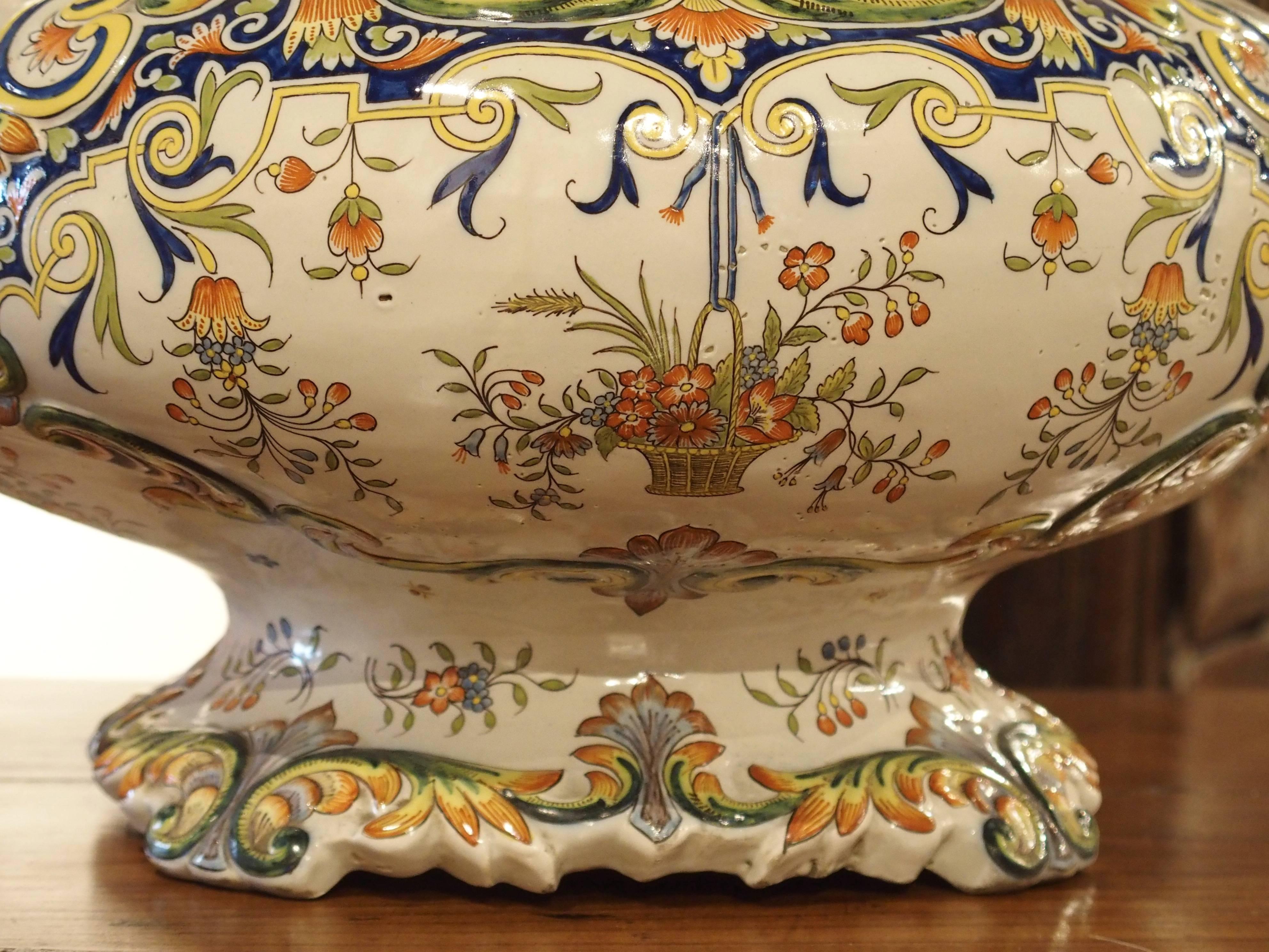 This elegant, two handled French urn has Rouen decoration throughout. It is hard paste, with a ground color of white and accompanying colors of orange, yellow, pale green, navy blue, and pale blue. These colors and the beautiful motifs are typical