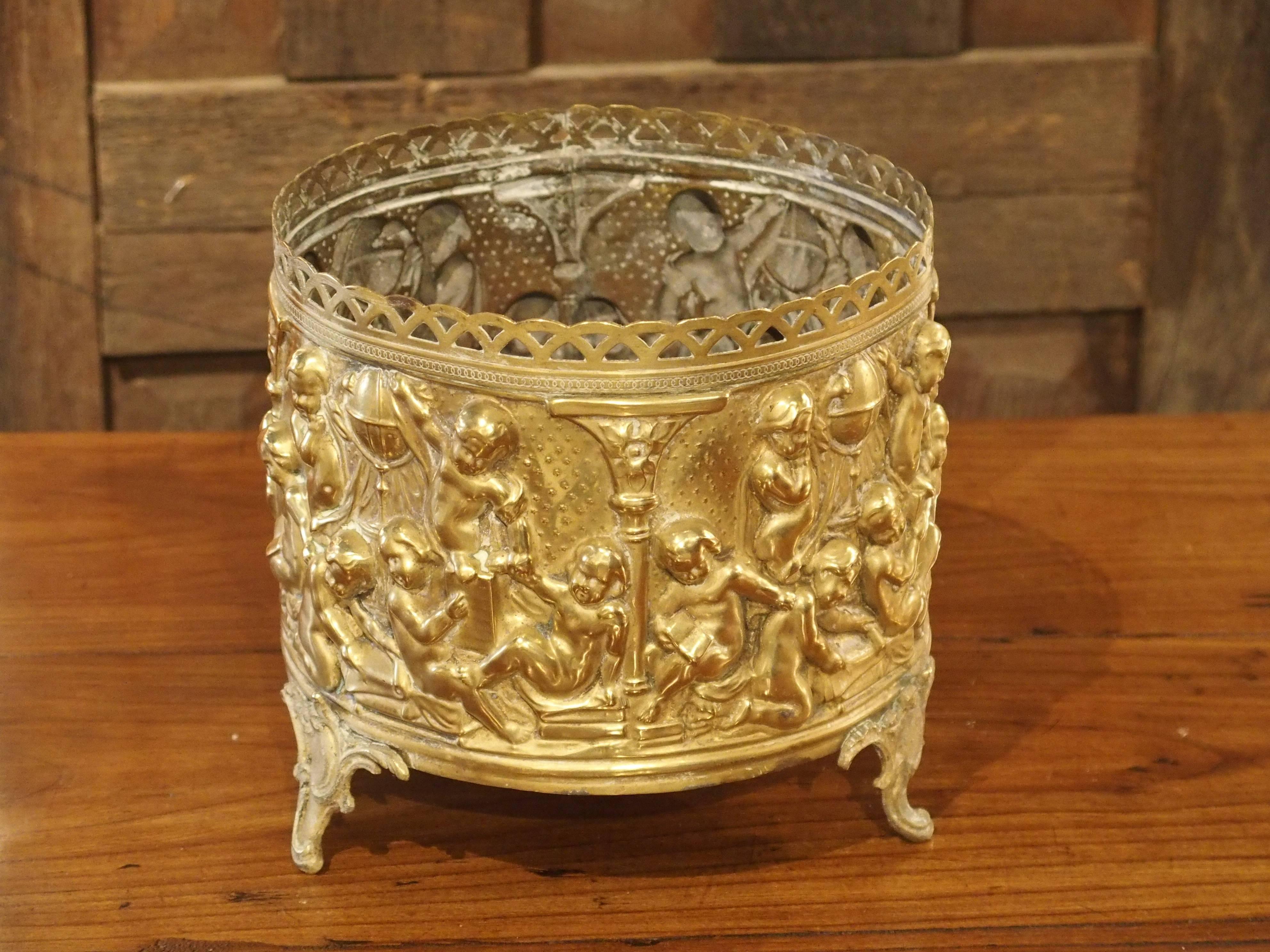 This charming antique French repousse planter depicts putti studying large terrestrial globes, scrolls, and books. It rests upon three foliate feet. A beautiful accessory for any area of the home, the French planter can stand on its own or with