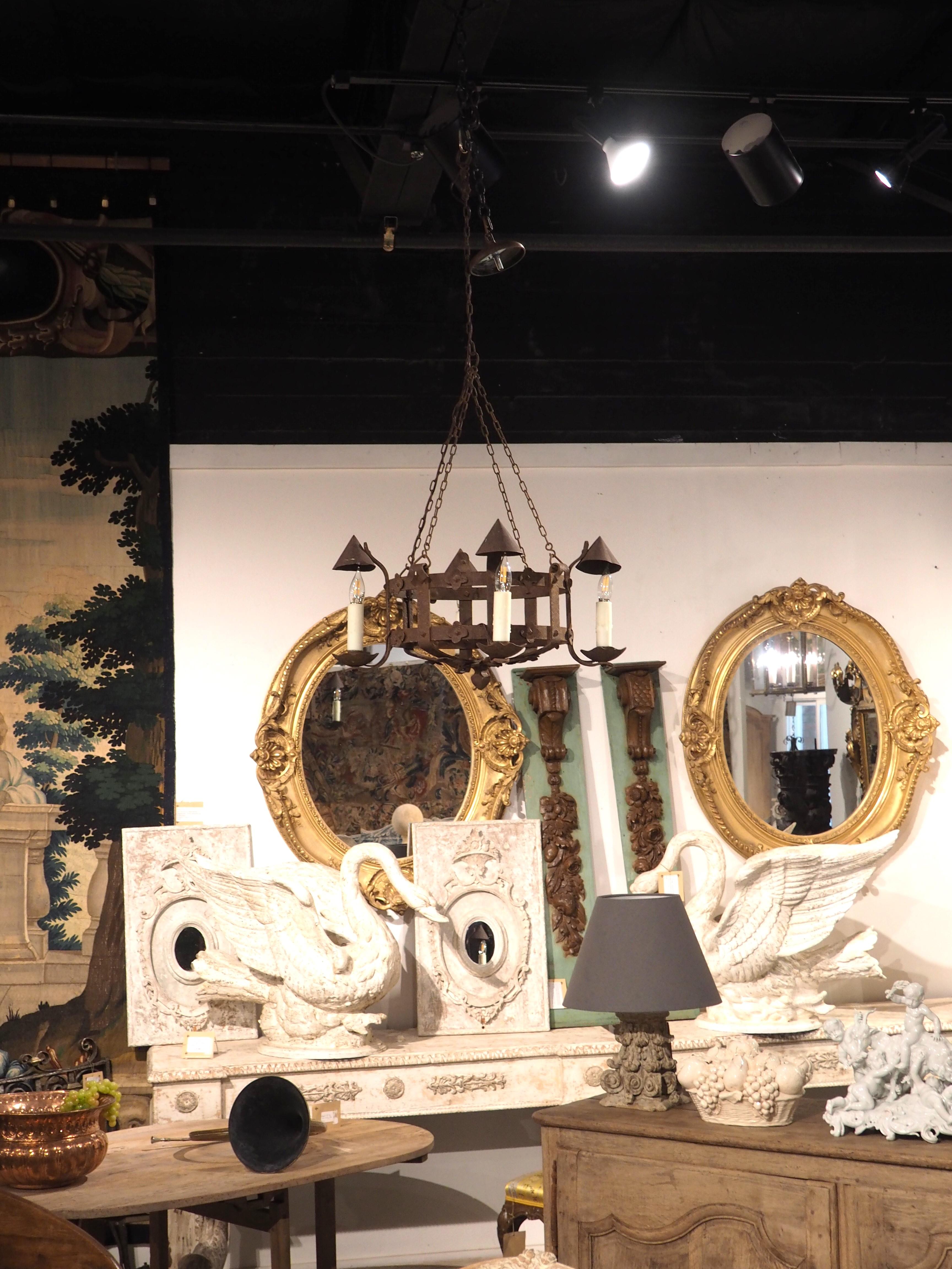 This antique French round two level chandelier has charming little pointed hats which rest over the candles or lights.  The bobeches are curved and scalloped, and they are attached with a curved iron band to the hats that is then attached to the