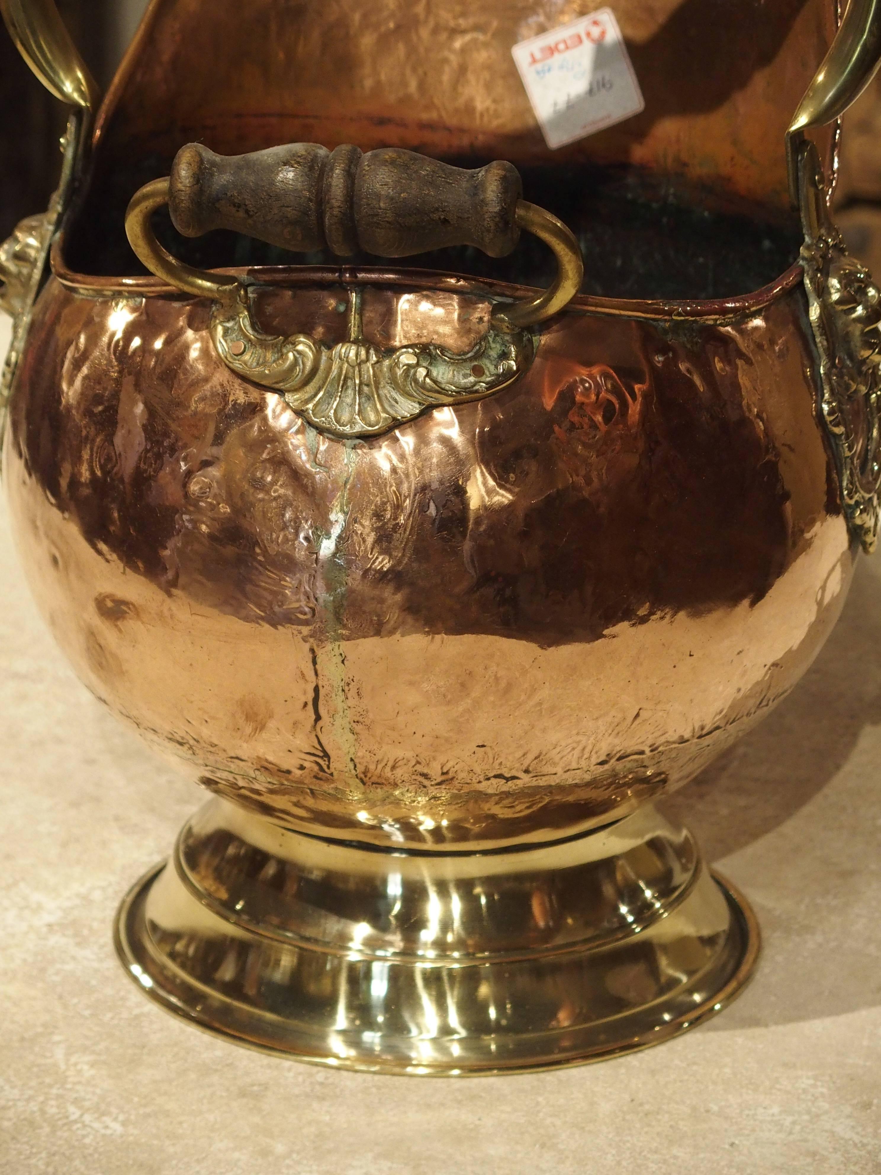 This beautiful French coal pail has been made from copper, brass and wood. As you can see, where the largest handle is attached to either side, there are fabulous lion’s head motifs. Beneath the smaller handle there is a stylized shell motif and two