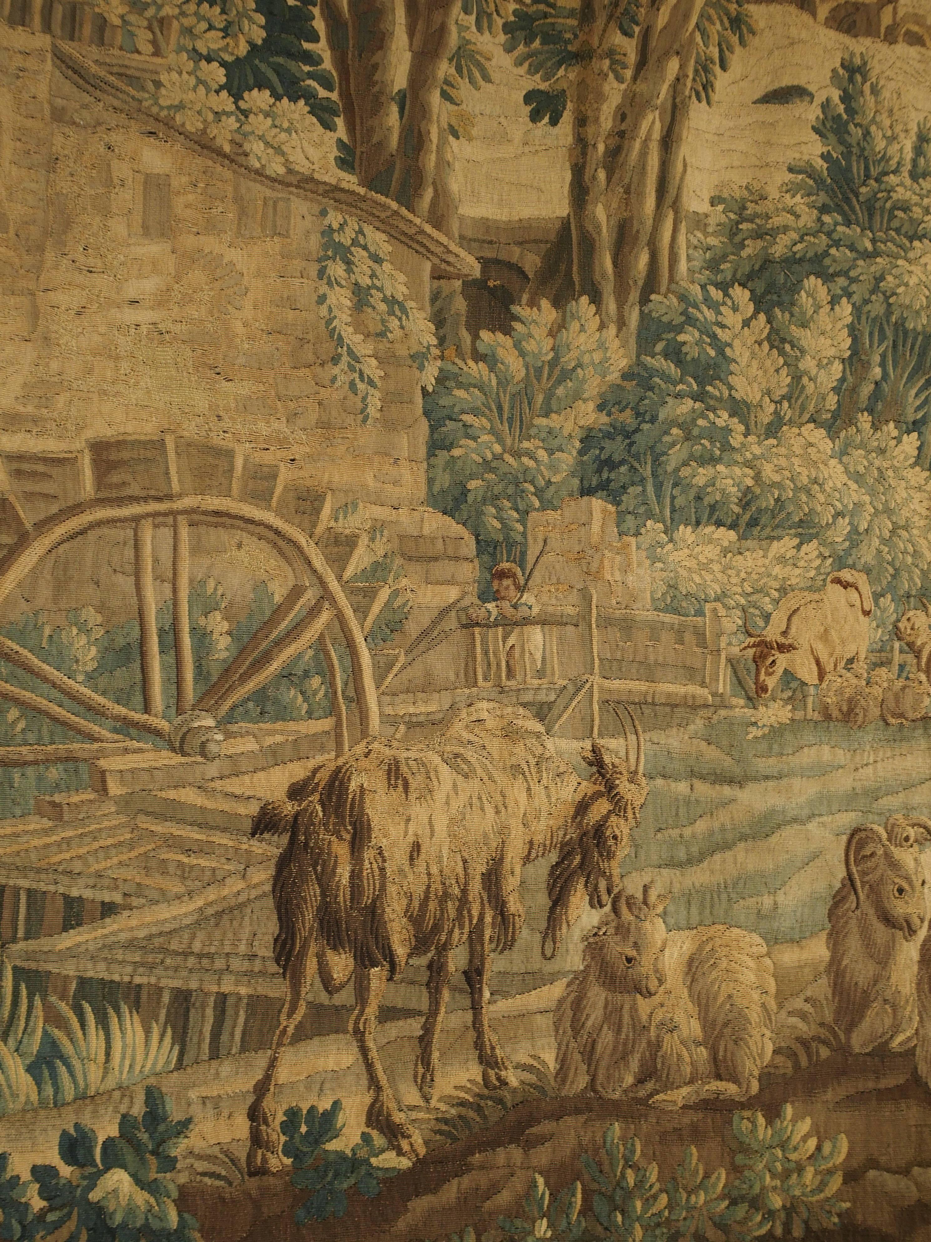 This stunning Aubusson tapestry was woven in the mid-18th century from silk and wool. It is after the work of the French artist Francois Boucher, titled “Le Moulin de Charenton”. The focal point of the tapestry scene is the stone house with a large