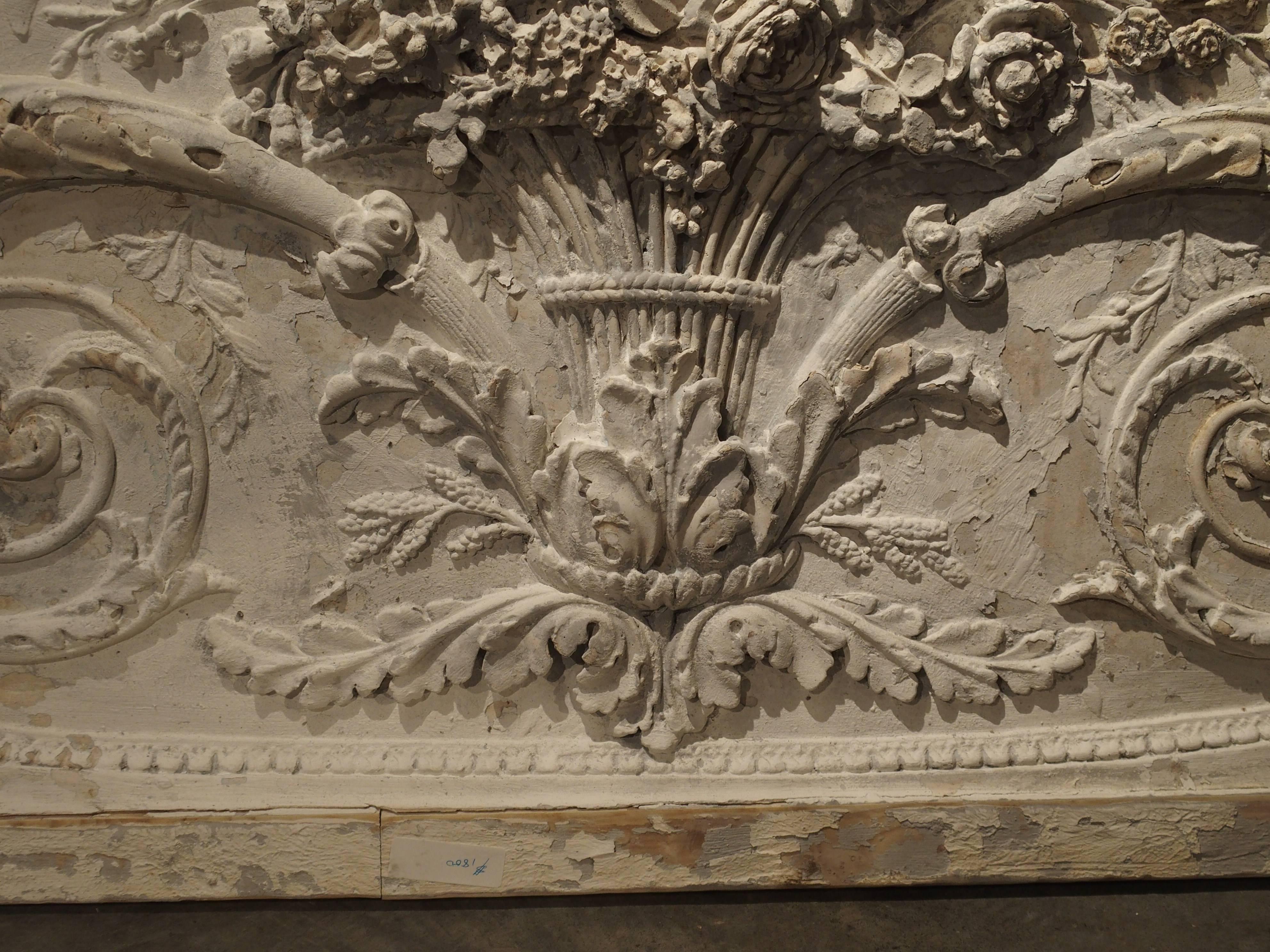 This beautiful panel is a parcel paint plaster bas relief from France. The framed plaster overdoor depicts classic scrolling rinceau growing from a central vase. Originally, these were placed over doors in French paneled rooms. Today, they can still