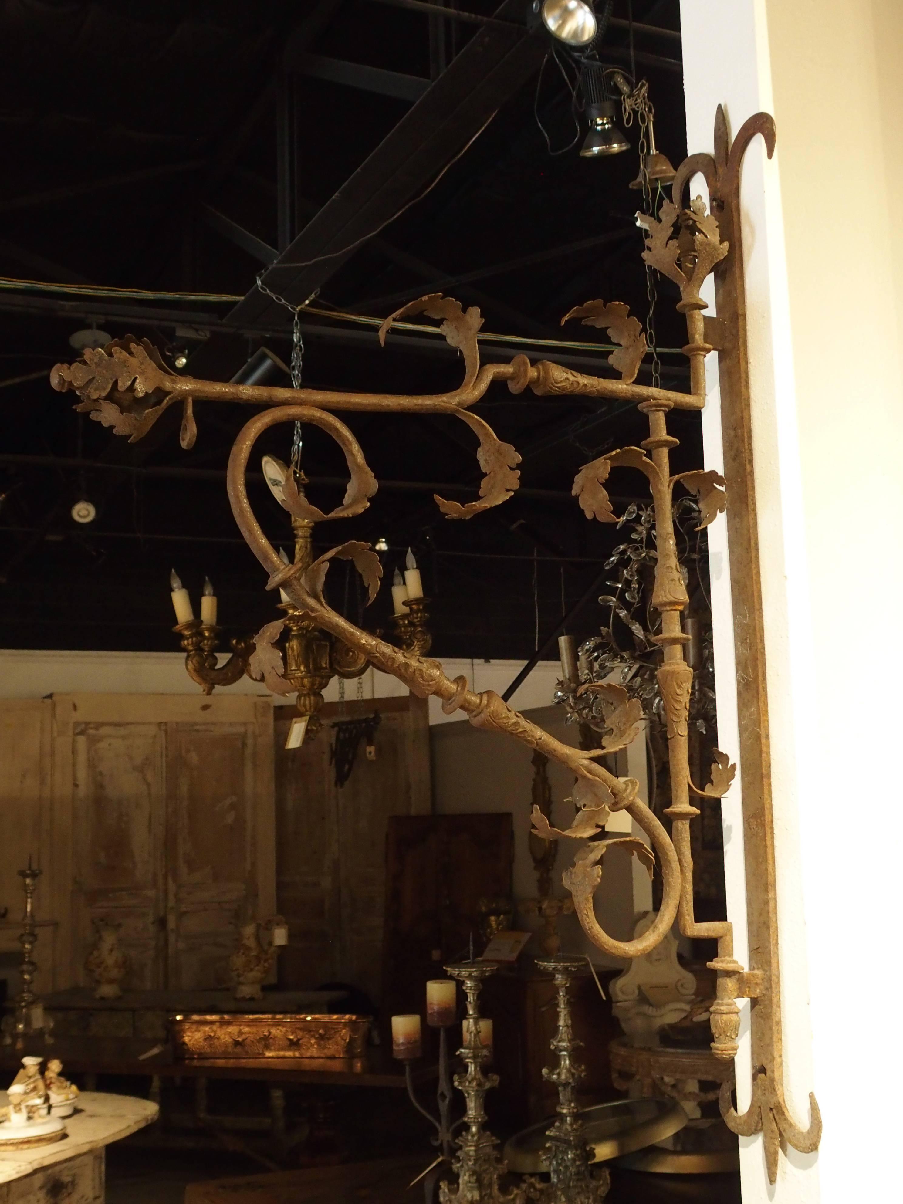This is a magnificent antique French iron store sign holder or lantern holder from the 1700s. There is a circular iron piece at the end of the top rod from which a sign or lantern would have hung. The main iron support is a vertical, wall mounted