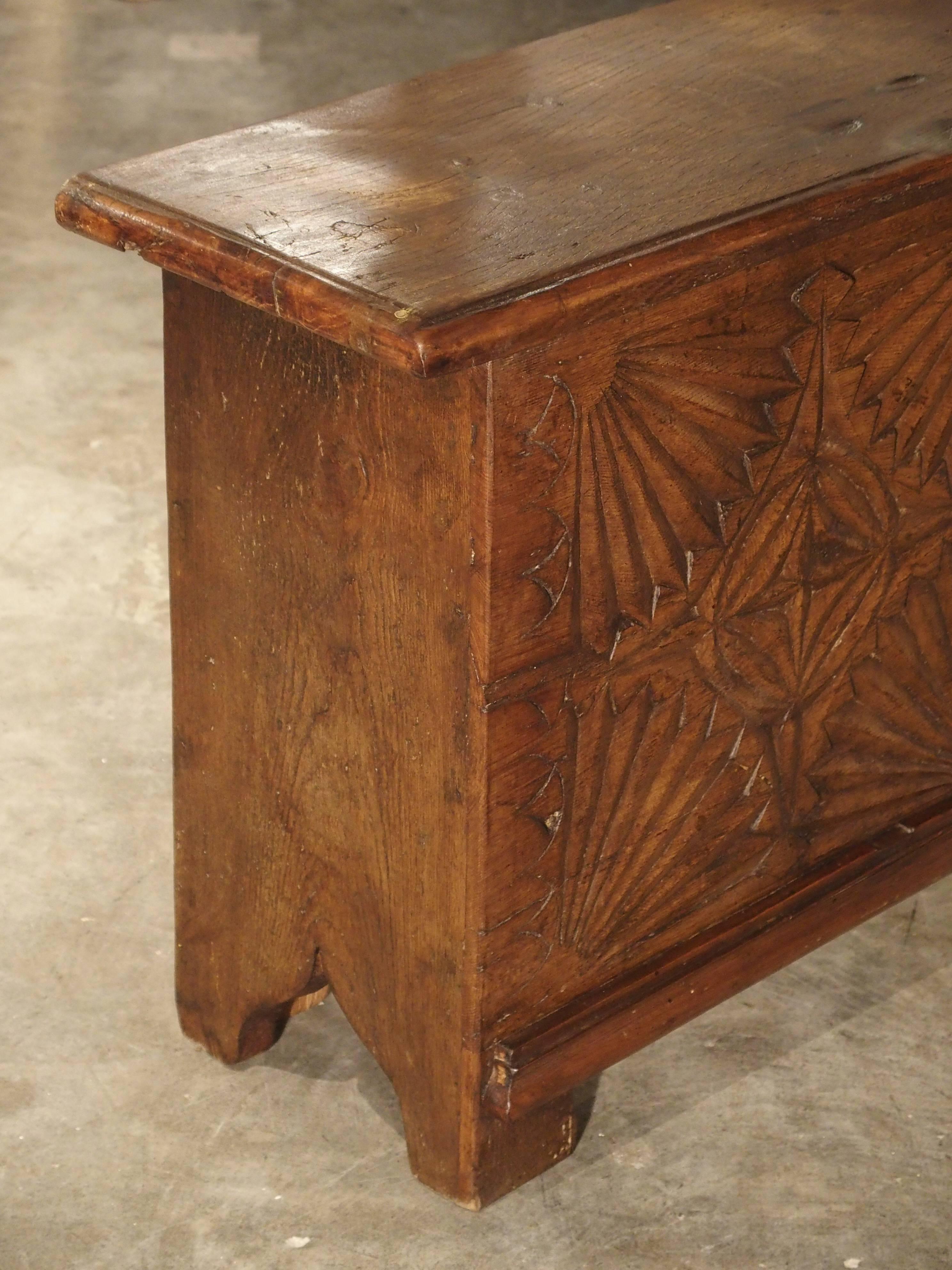This shallow trunk from France has been constructed from French oak and has some antique elements. The front panel has two sections of four fan shaped motifs. At the centre is a stylized quatrefoil inside a carved circle. The centre panel has the