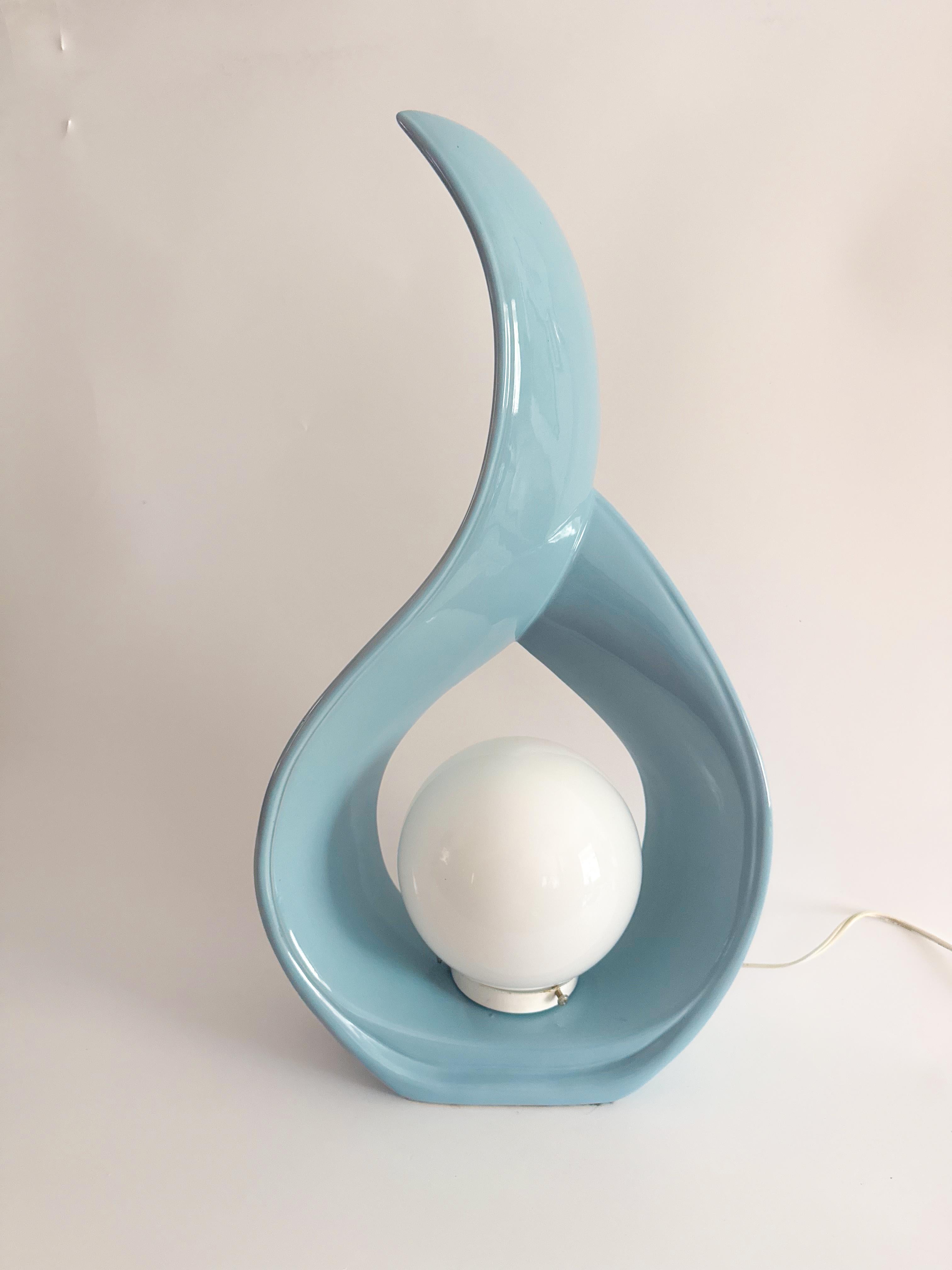 Una rara gemma di perfezione pastello: questa lampada scultorea a goccia degli anni '80 stupisce per l'originale smalto azzurro cielo, quasi impossibile da trovare oggi. La sua elegante forma a nastro si incurva verso l'alto intorno a un globo