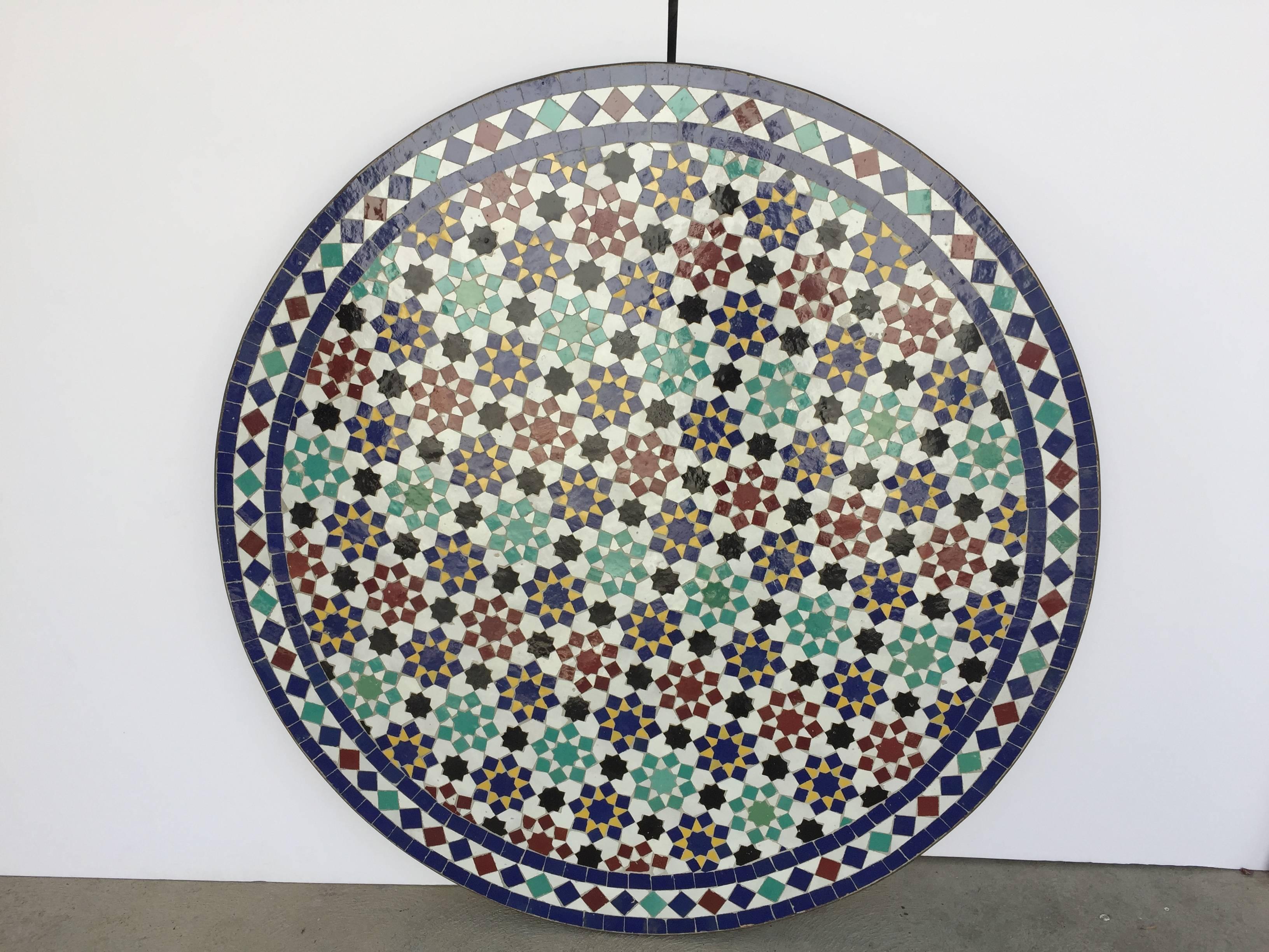 Moroccan round mosaic tile table delicately handcrafted by expert artisans in Fez, Morocco, using reclaimed old glazed tiles inlaid in concrete with traditional Islamic Moorish geometrical design in white, blue, red, green colors.
Moroccan mosaic