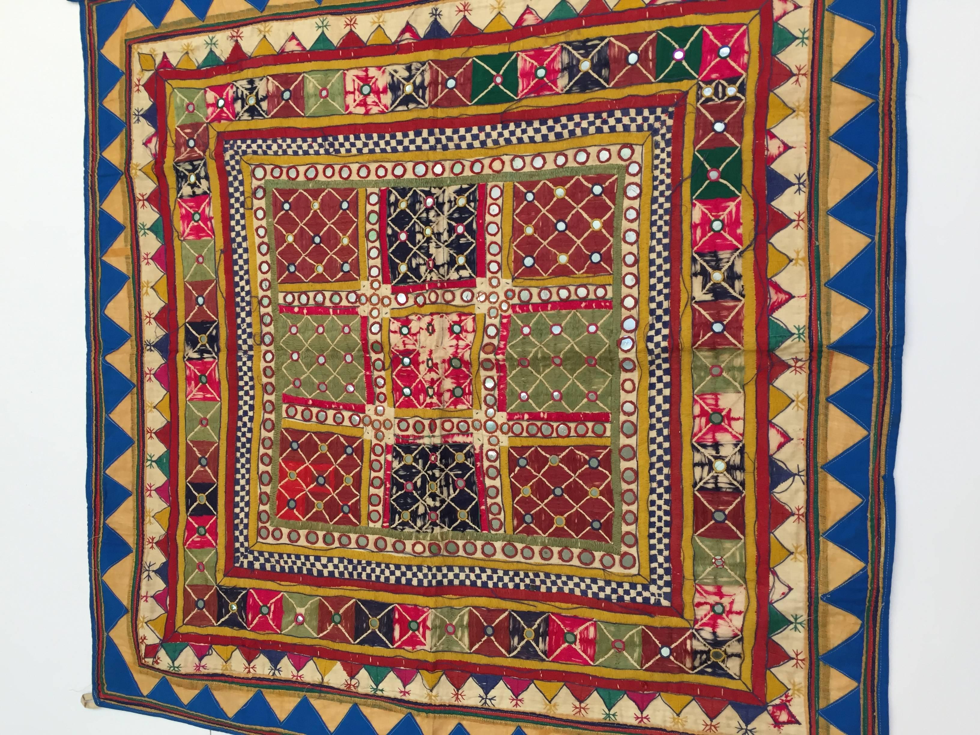 Embroidered ceremonial cloth, square hanging textile.
By the Mahajan people, Kathiavad, Saurashtra.
The embroidery is worked with geometric stitch on linen in red, gold, green, orange, blue, and decorated with mirrors and used for wedding