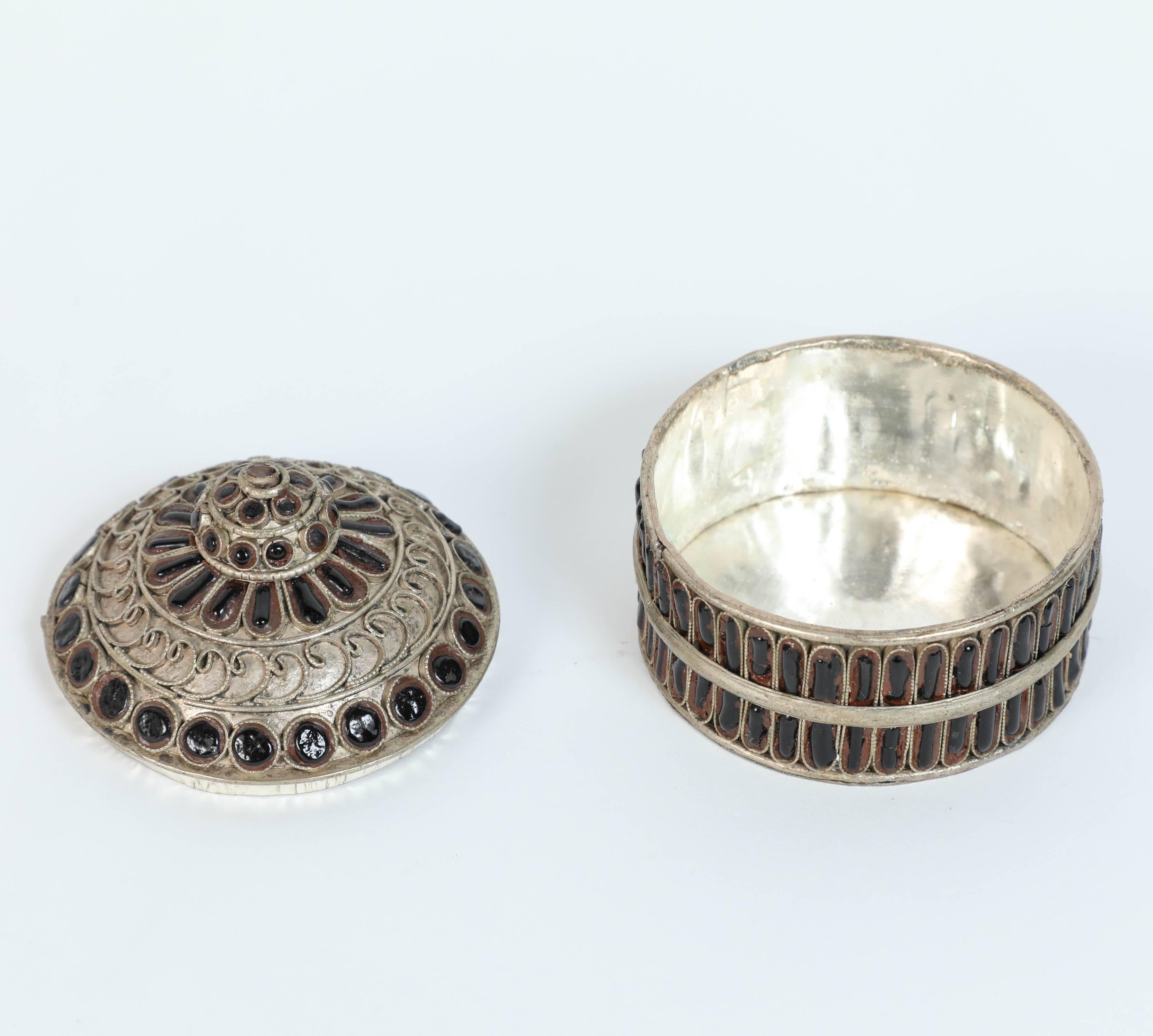 Silvered metal lidded snuff box of a circular form.
Designed into two detached sections, finely handcrafted and decorated with scrollwork designs with black stones inlay and lots of great detail.
Snuff or betel box Taj Mahal Jaipur India.
Size: