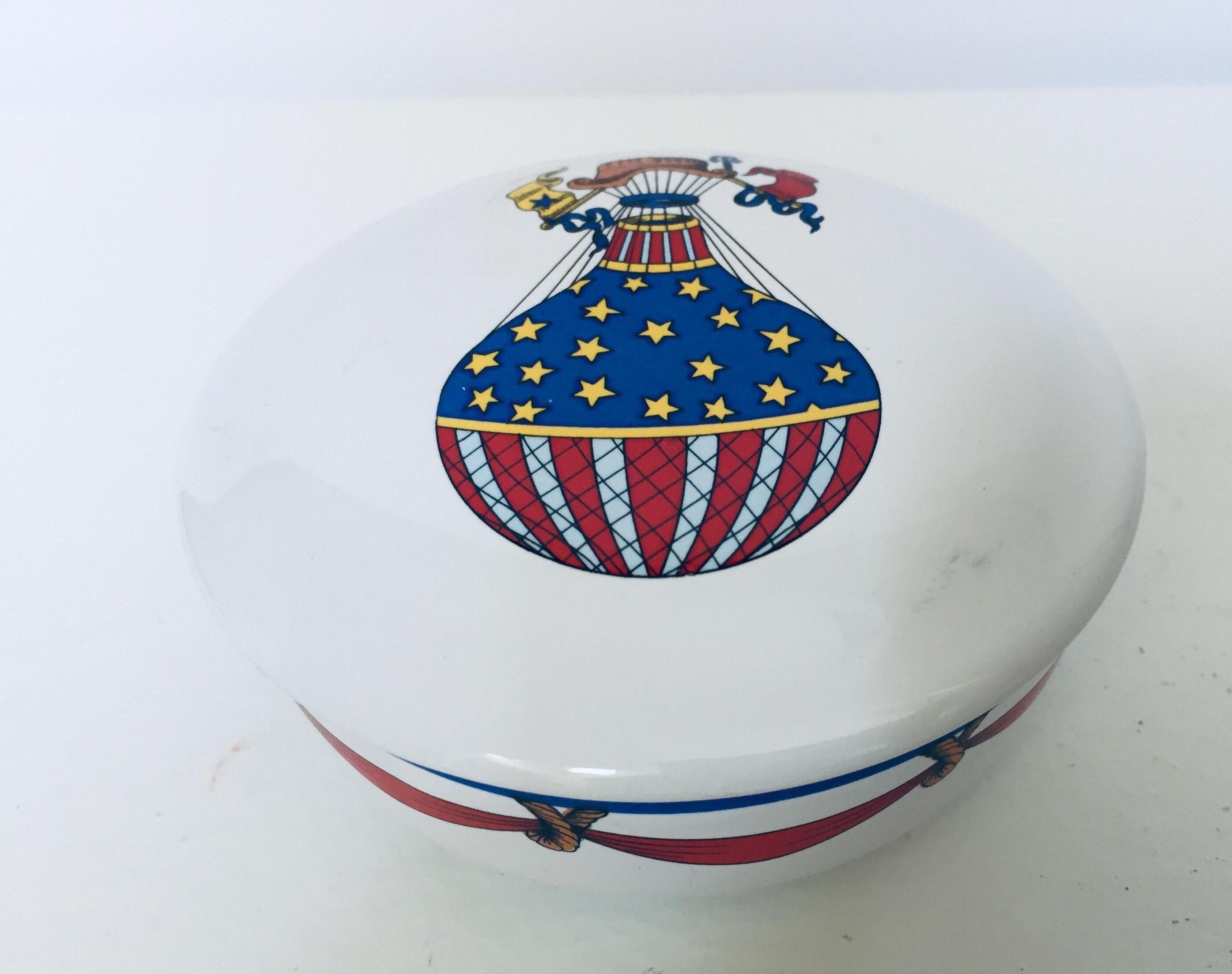 Tiffany & Co. white porcelain round dish, trinket box.
The porcelain lid cover is decorated with a balloon in the American flag colors, red and blue with yellow stars.
The round white porcelain dish was designed by Tiffany & Co.
and made in