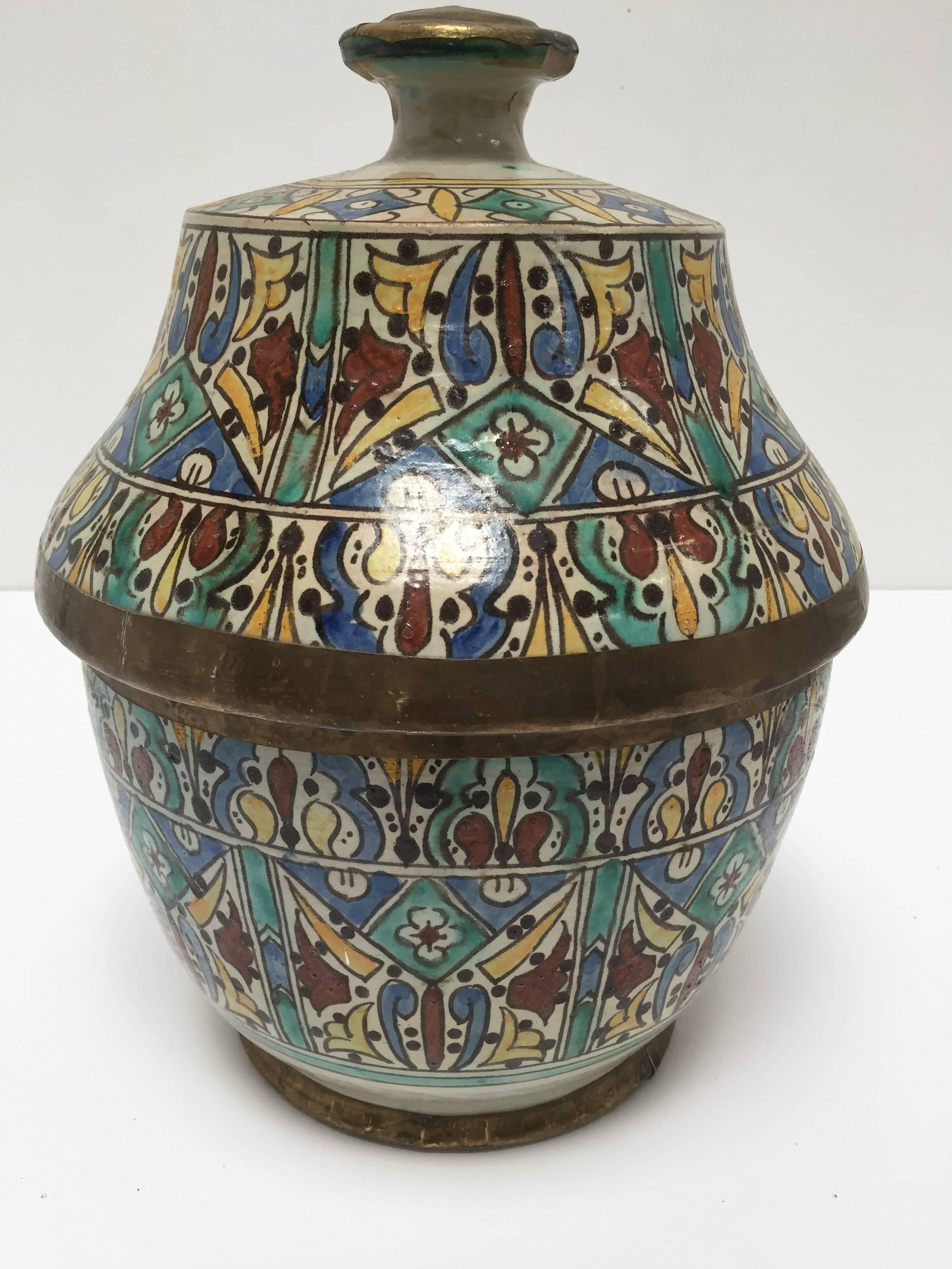 Large Moroccan glazed polychrome ceramic jar tureen with cover.
Hand painted ceramic Jubbana, handcrafted by skilled Moroccan artisans in Fez Morocco.
Moorish designs in turquoise, blue, saffron yellow, prune and ivory color with brass decorated