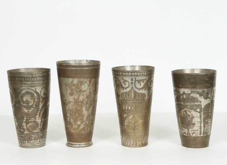 Set of 4 antique Middle Eastern engraved brass and silvered metal beakers. 
Moroccan style metal beakers with hand chiseled and hand-carved Indian floral motifs.
Great Anglo Raj decorative art metal objects.
4 larger ones are 7