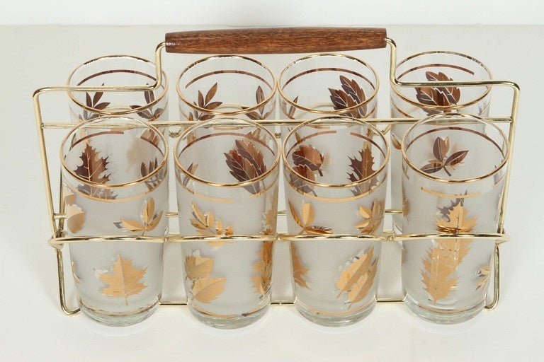 Elegant Vintage Libbey barware glasses with leaves pattern in a gold finish. 
Set includes eight highball glasses in a polished brass cart with a wood handle.
Mid-Century Modern vintage glasses. Hollywood Regency style.
The pattern on frosted glass