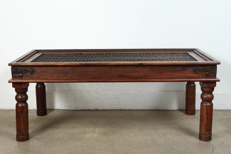Spanish style coffee table with iron inset jail work.
Large coffee table in solid teak wood with nailheads and metal accents support, very nicely carved legs and sides and the corners are reinforced with metal iron pieces. Spanish, Portuguese style