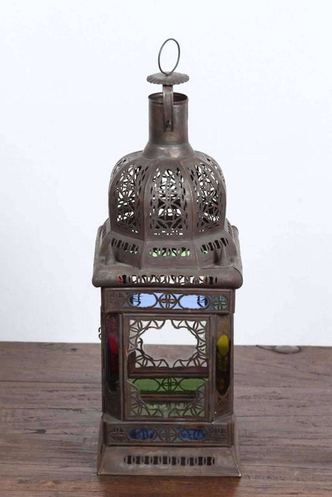Moroccan Moorish square metal and glass candle lantern or pendant.
Square shape with clear and colored glass in red, green, blue and amber color.
Vintage bronze rust finish metal hurricane candle lamp.
There is a glass bottom and a small door to