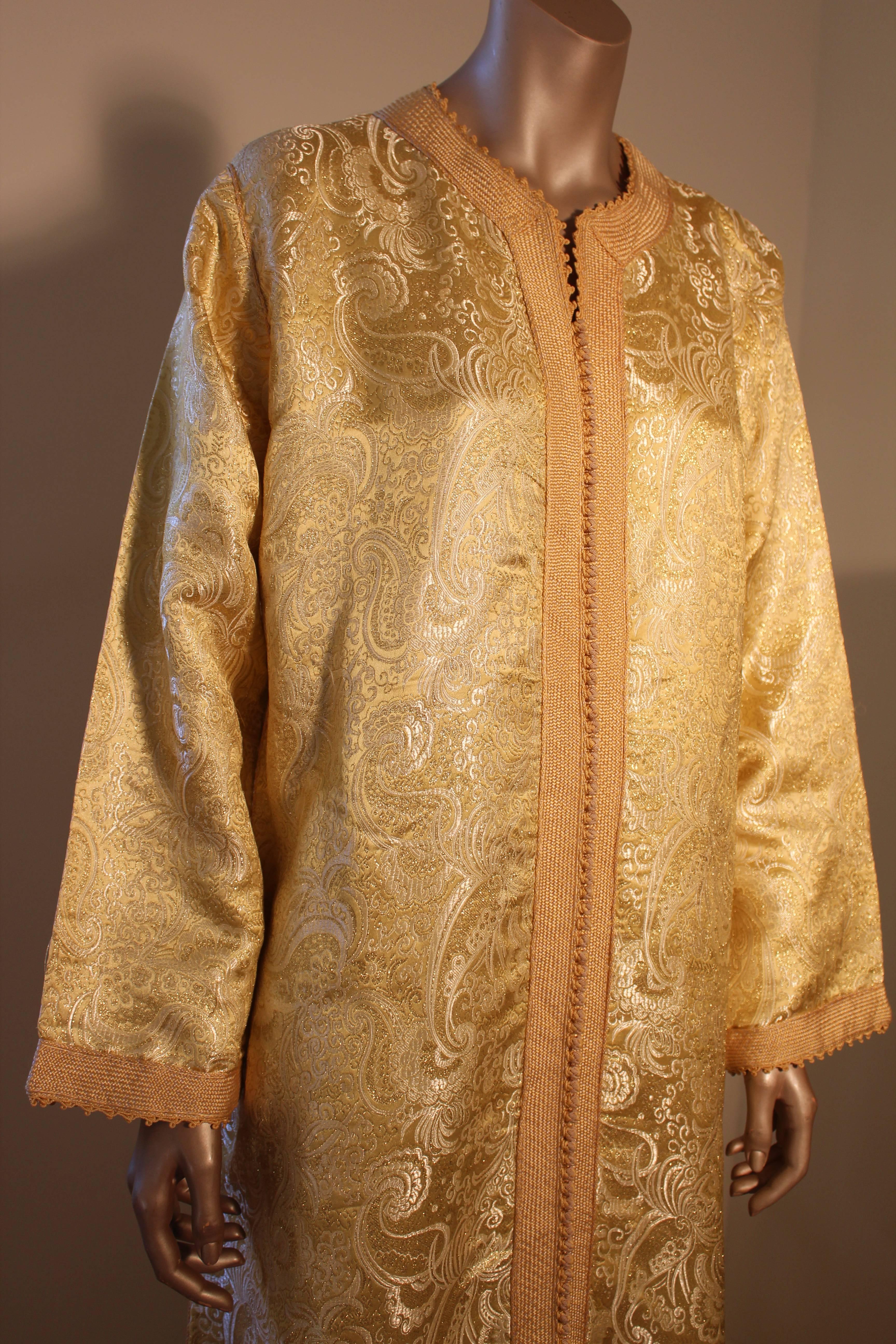 Moroccan vintage exotic gold brocade caftan gown, circa 1970s.
The luxurious kaftan is designed with brilliant gold metallic fabric.
The front of the elegant Kaftan gown is embellished at the front with woven gold buttons and loops that run down the
