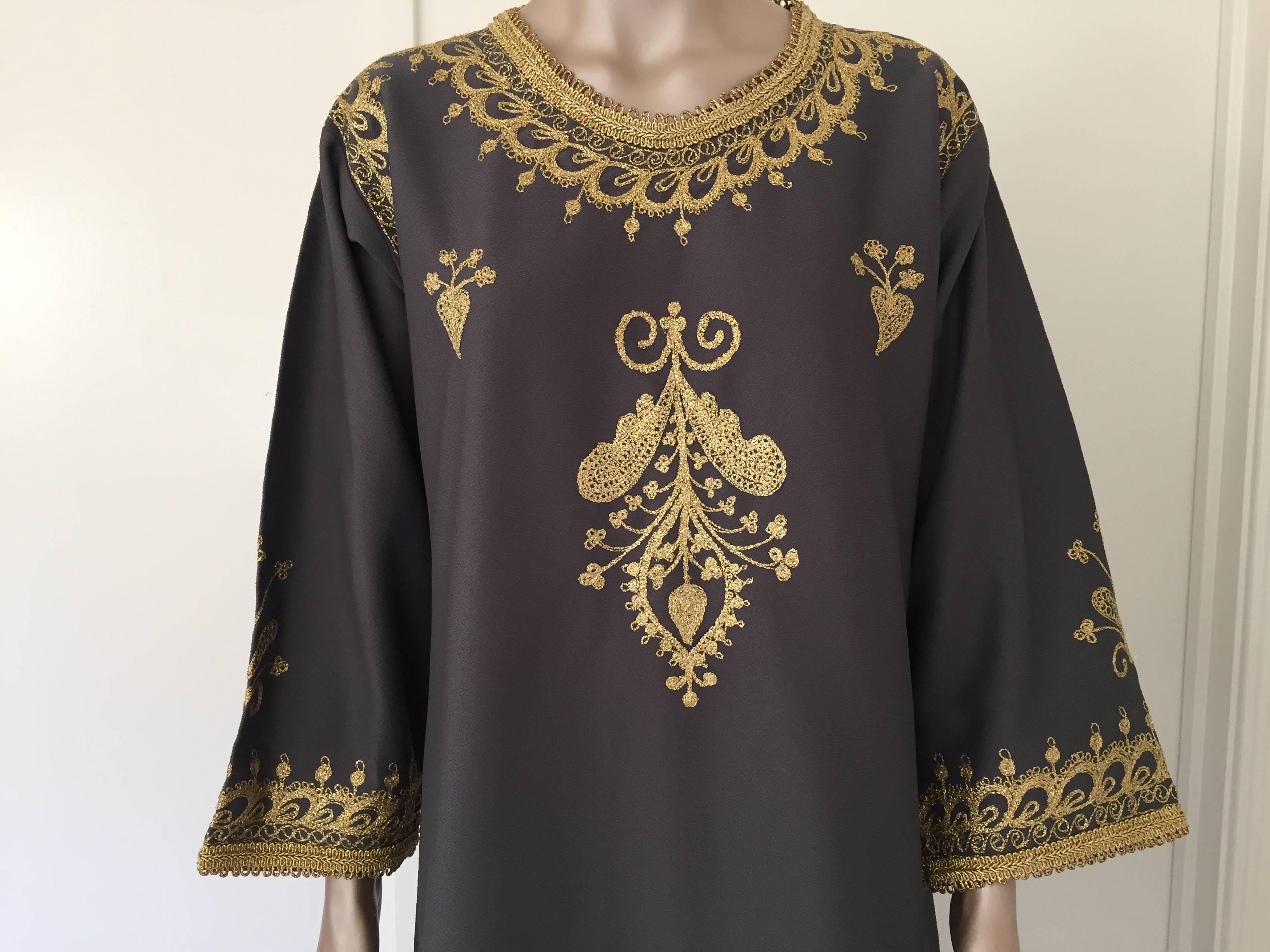 Elegant Moroccan caftan embroidered charcoal grey color with gold threads.
Circa 1970s.
This long maxi dress kaftan features a traditional Egyptian neckline, with side slits and embellished sleeves with gold Moorish designs.
In Morocco, fashion