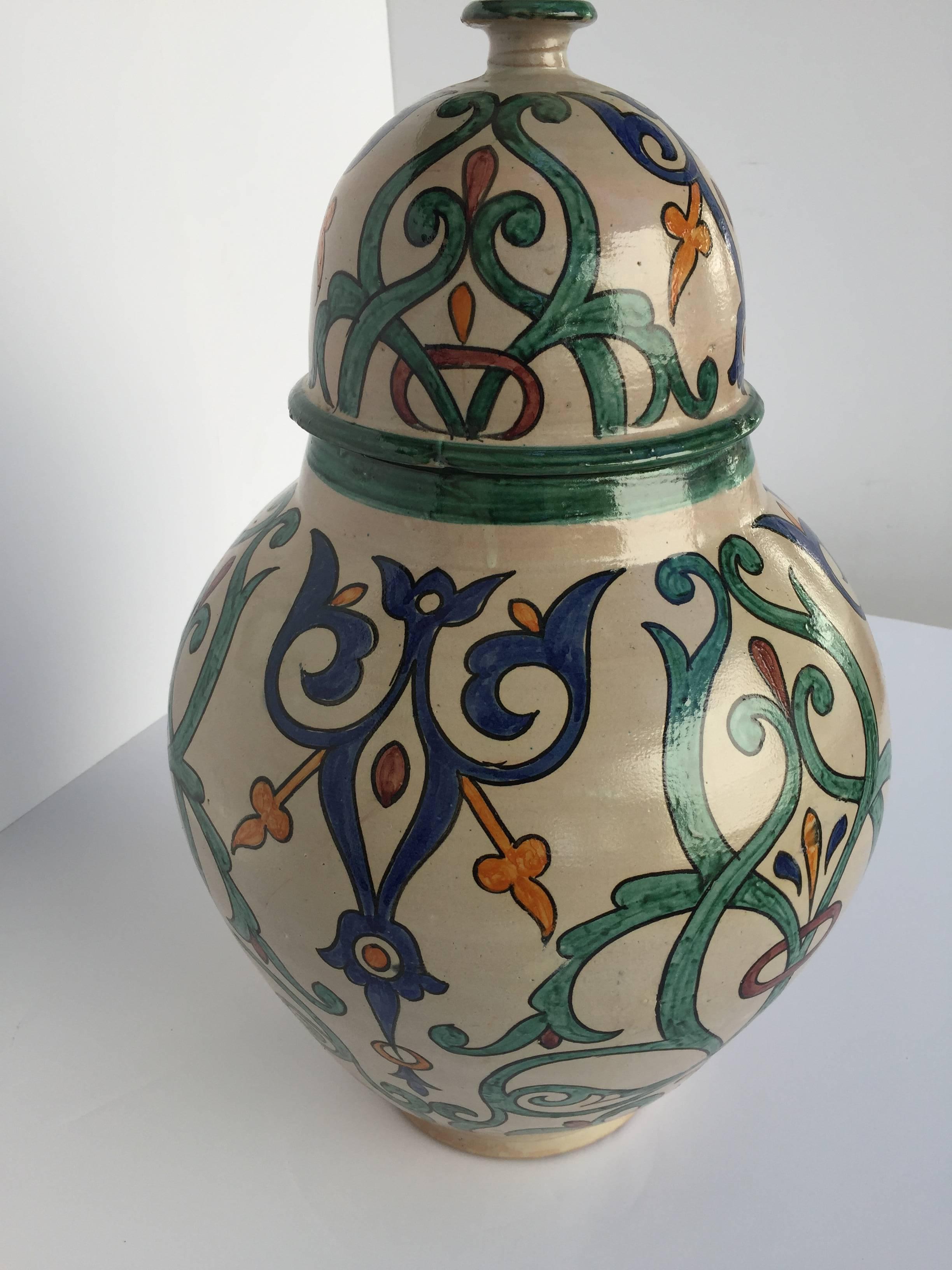 Large Moroccan glazed ceramic urn with lid from Fez. 
Granada style ceramic handcrafted and hand-painted with Moorish foliate designs in blue, teal, Safran and red colors on ivory background.
A pair is available price is for 1.
Large size: 25 in.