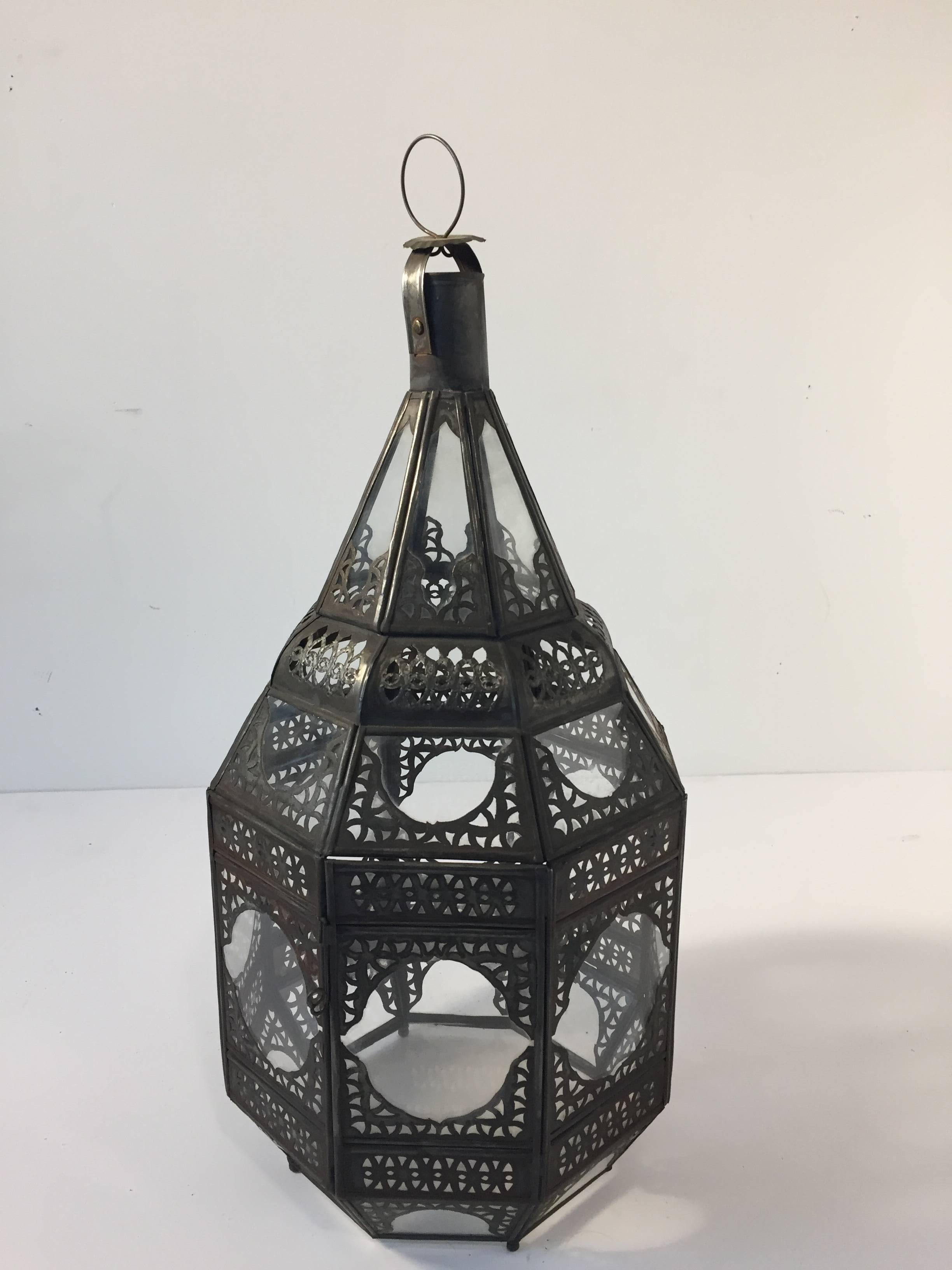 Moroccan Moorish clear glass lantern with intricate metal filigree.
Octagonal shape, delicately handcrafted by artisans in Morocco.
Bronze metal color finish.
Could be used with candle or rewired for electricity.
Multiple available contact
