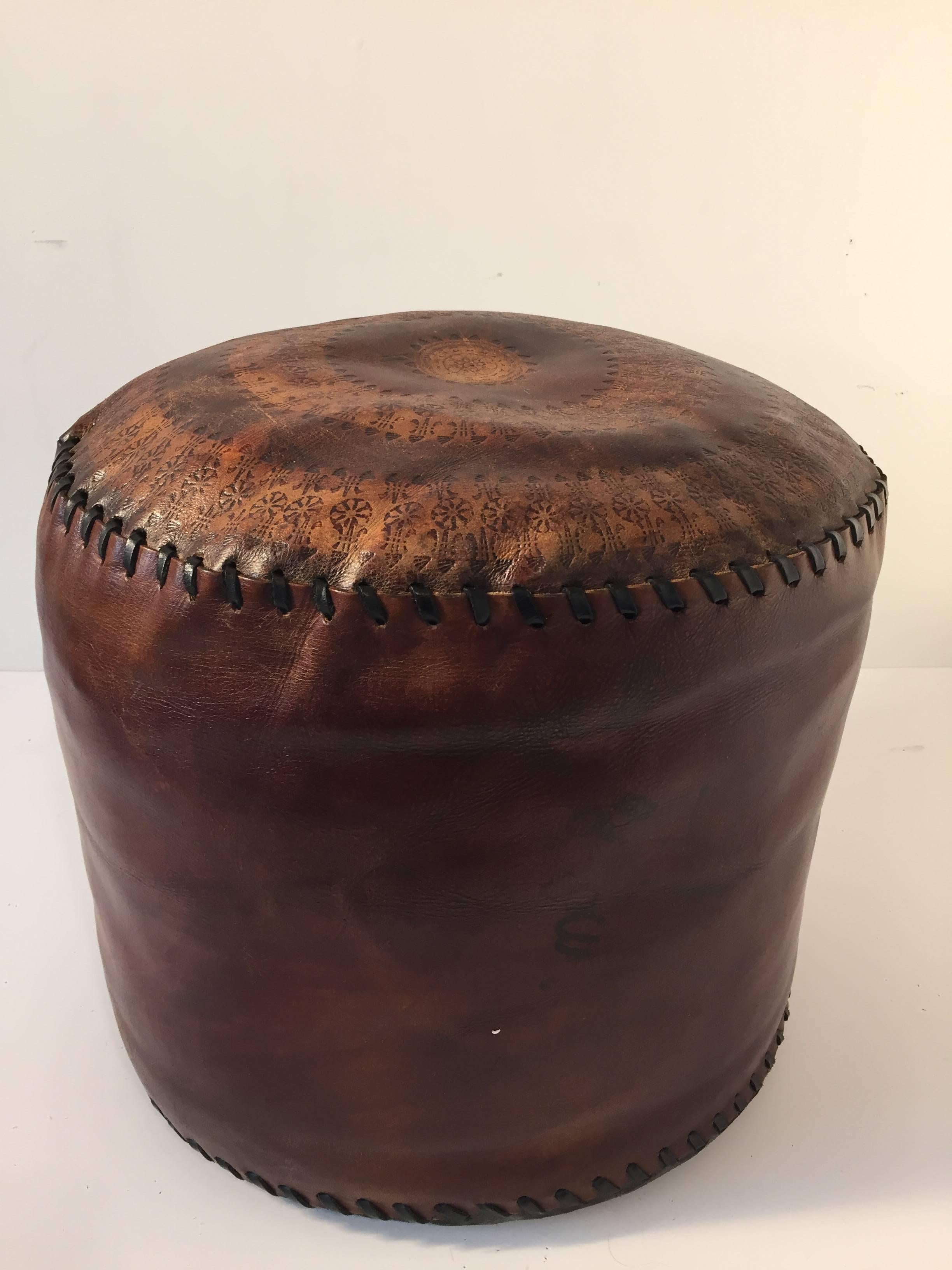 Vintage hand tooled African brown leather pouf.
Nice dark patinated leather with flat top embossed with tribal design and two-tone brown colors.
Size: 16 in. D x 15 in H.