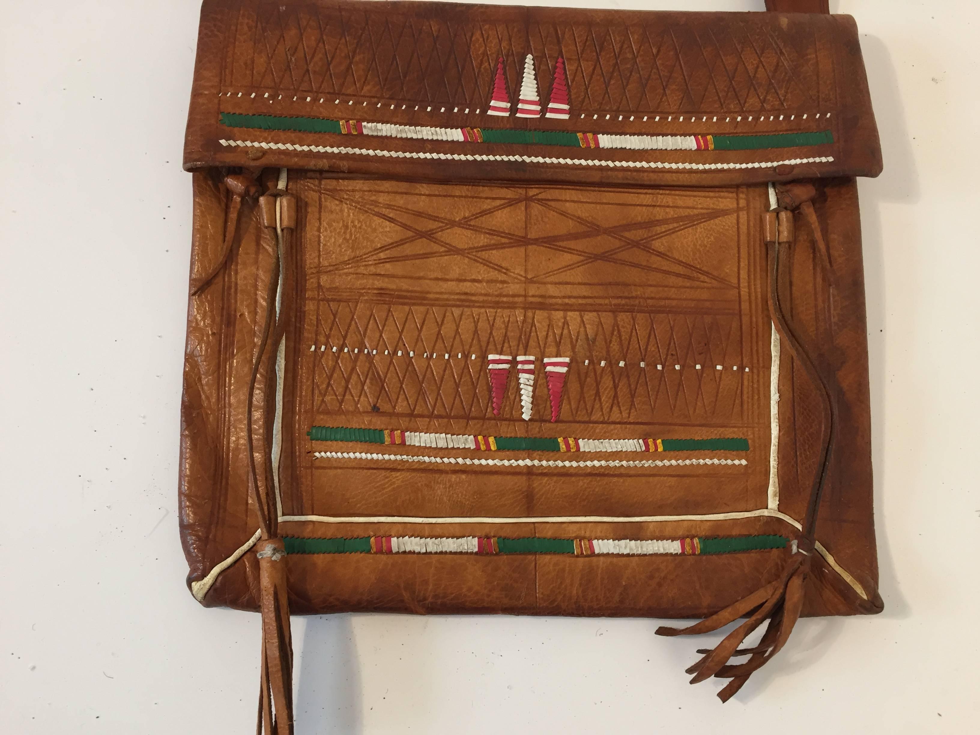 Old leather African Moroccan satchel bag with flap decorated with tribal Tuareg embroideries.
Hand-tooled in south Morocco, this is an old antique man shoulder slim bag, merchants in Morocco when travelling used this bag under their coat to put