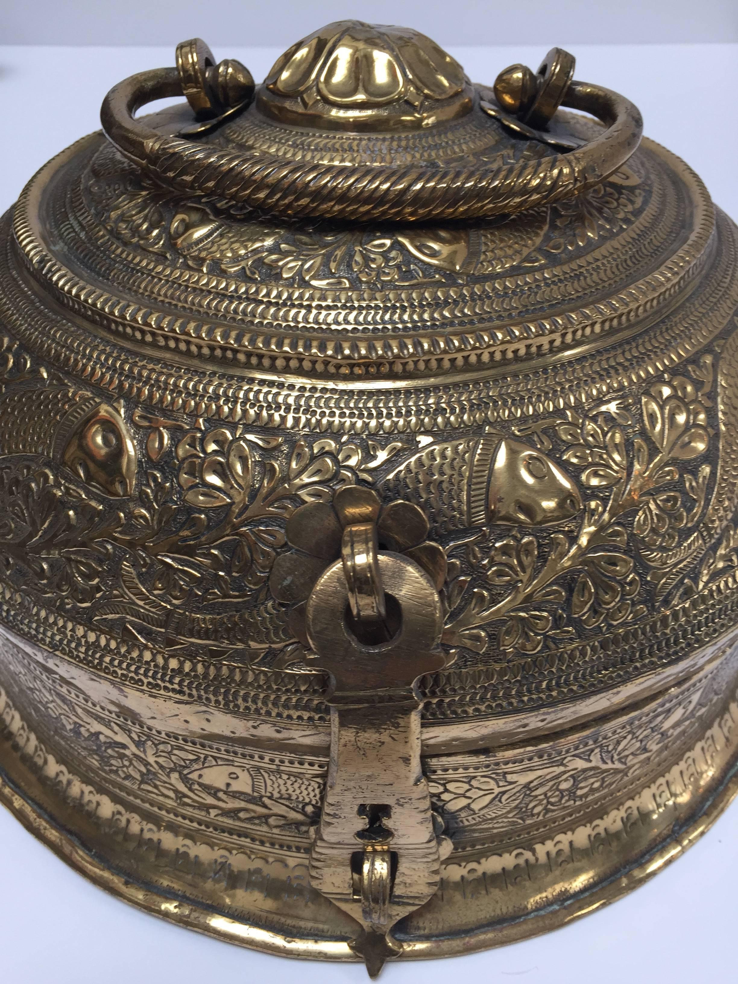 Beautiful 19th century large hand-crafted decorative round polished brass box with lid delicately and intricately hand-hammered with repousse floral and fishes designs.
Engraved with intricate designs on the lid which has a carved floral design