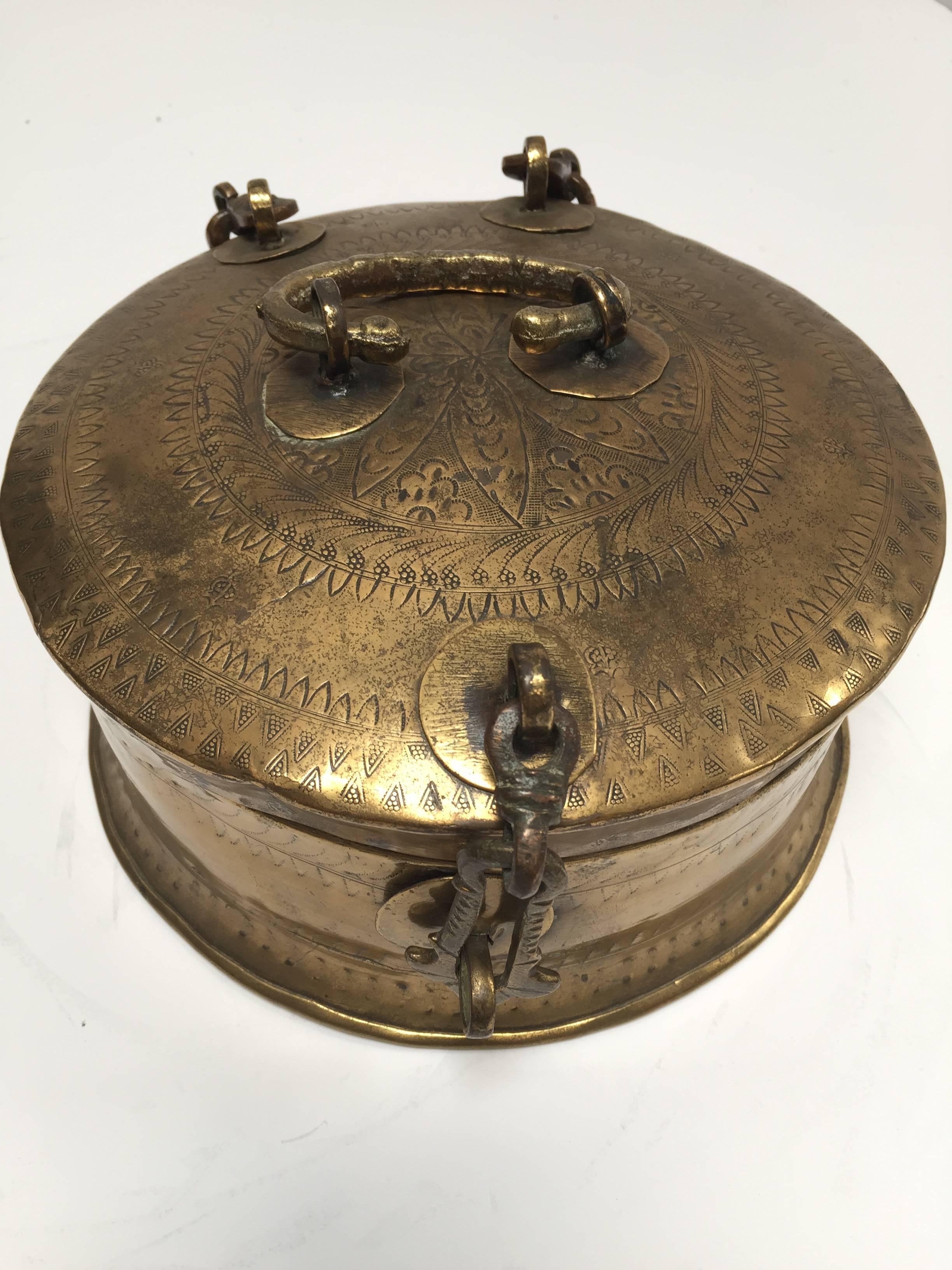 Handcrafted decorative round brass Anglo Indian lidded box with latch and a top handle.
Delicately and intricately hand-chased with geometric designs. 
Probably used as a tea caddy. 
Exquisite conversation museum quality piece with a very nice
