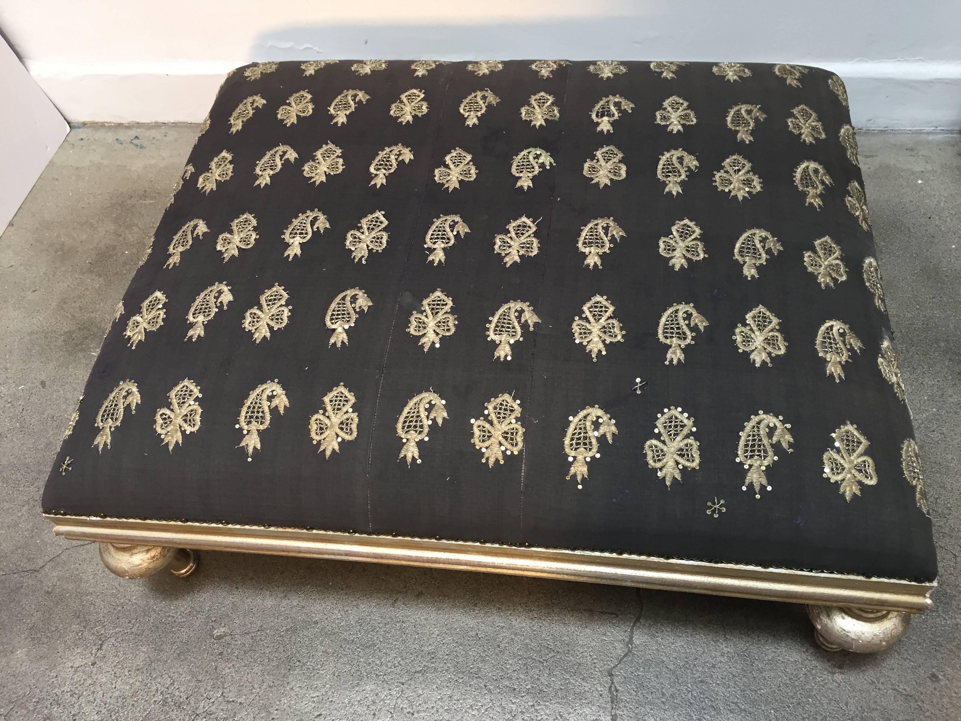 Beautiful Middle Eastern coffee table or ottoman from Lebanon.
The seat is upholstered with an old black Moorish textile embroidered with gold and silver treads. The frame has turned legs in gilt color. 
Decorative with antiqued bronze spaced