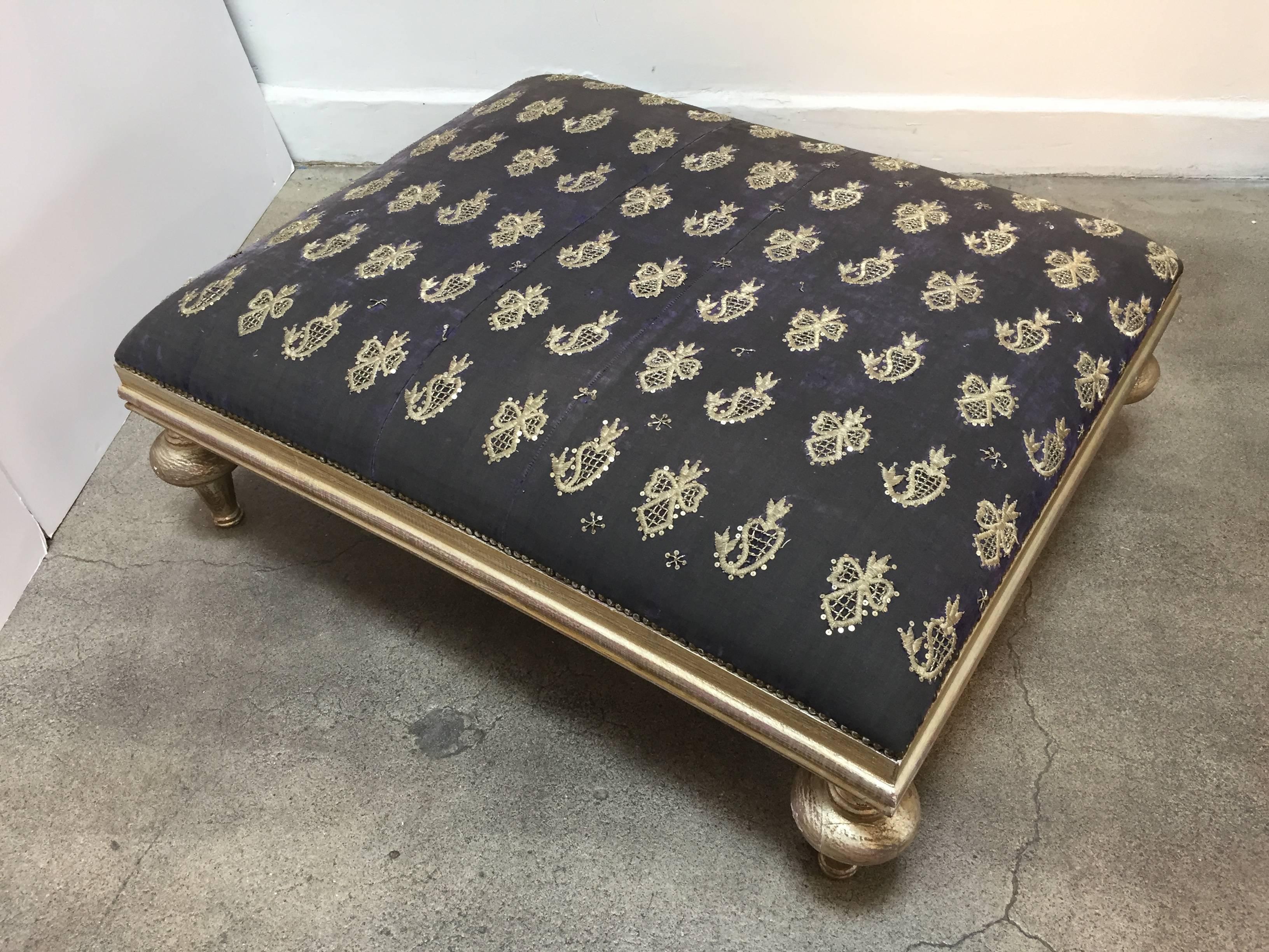 Beautiful Middle Eastern coffee table or ottoman from Lebanon.
The seat is upholstered with an old black Moorish textile embroidered with gold and silver treads. The frame has turned legs in gilt color. 
Decorative with antiqued bronze spaced