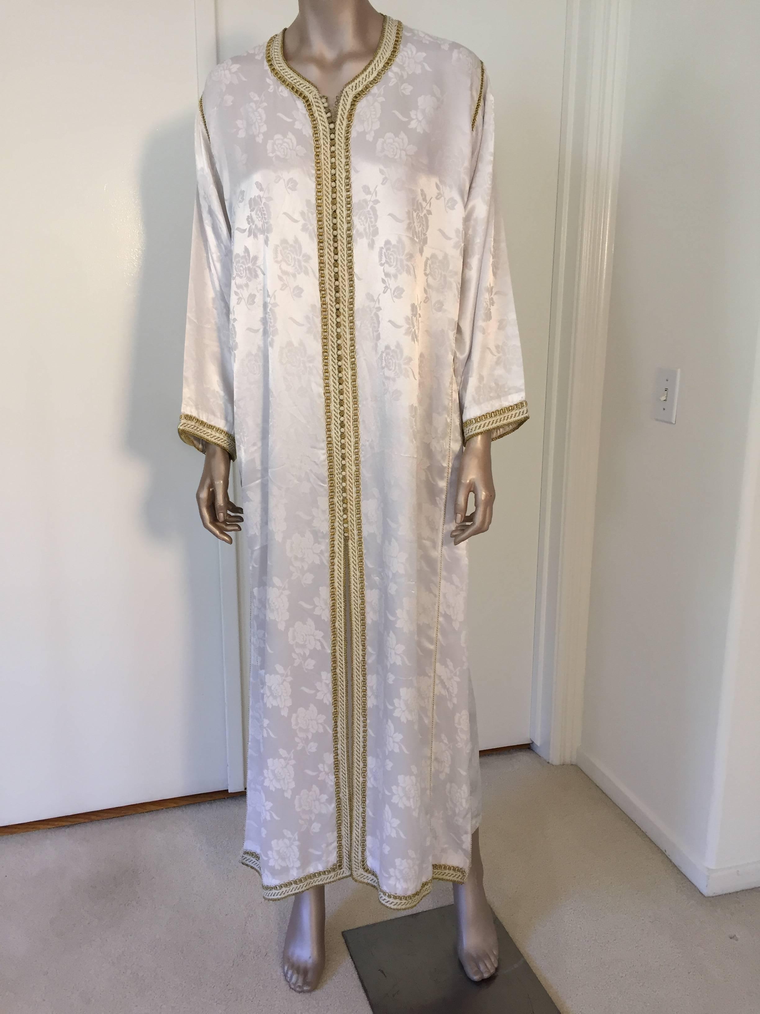 Elegantes marokkanisches Kaftan-Kleid mit weißer Stickerei und Goldverzierung, um 1970. Dieser Kaftan im langen Maxikleid ist vollständig von Hand bestickt und verziert. Einzigartiges marokkanisches Abendkleid aus dem Nahen Osten.
Der Kaftan hat