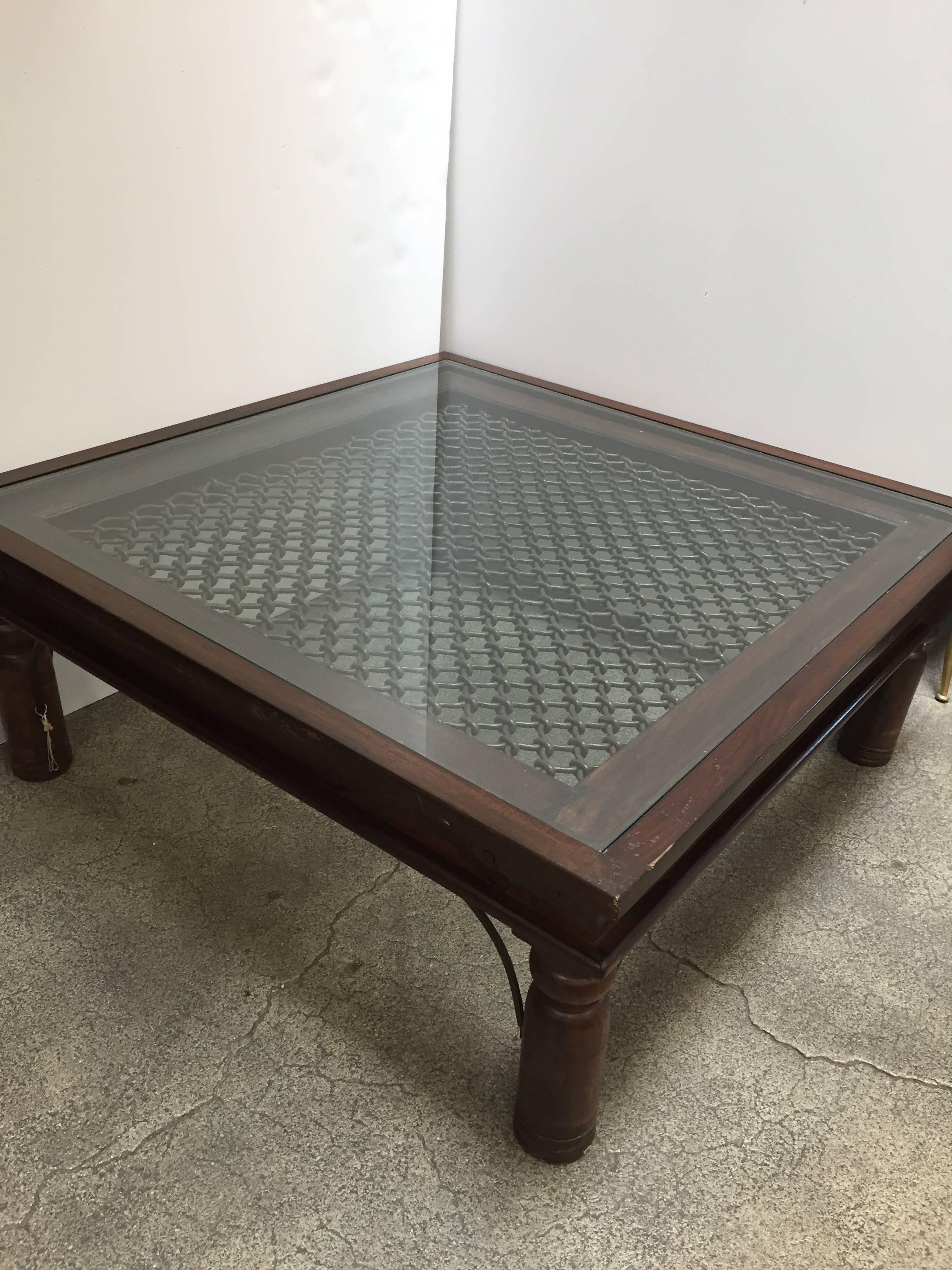 Anglo Indian style wooden coffee table with iron inset work and glass. 
Large coffee table in solid teak wood with nailheads and metal accents support, very nicely carved legs, sides and corners are reinforced with metal iron pieces. 
Spanish,