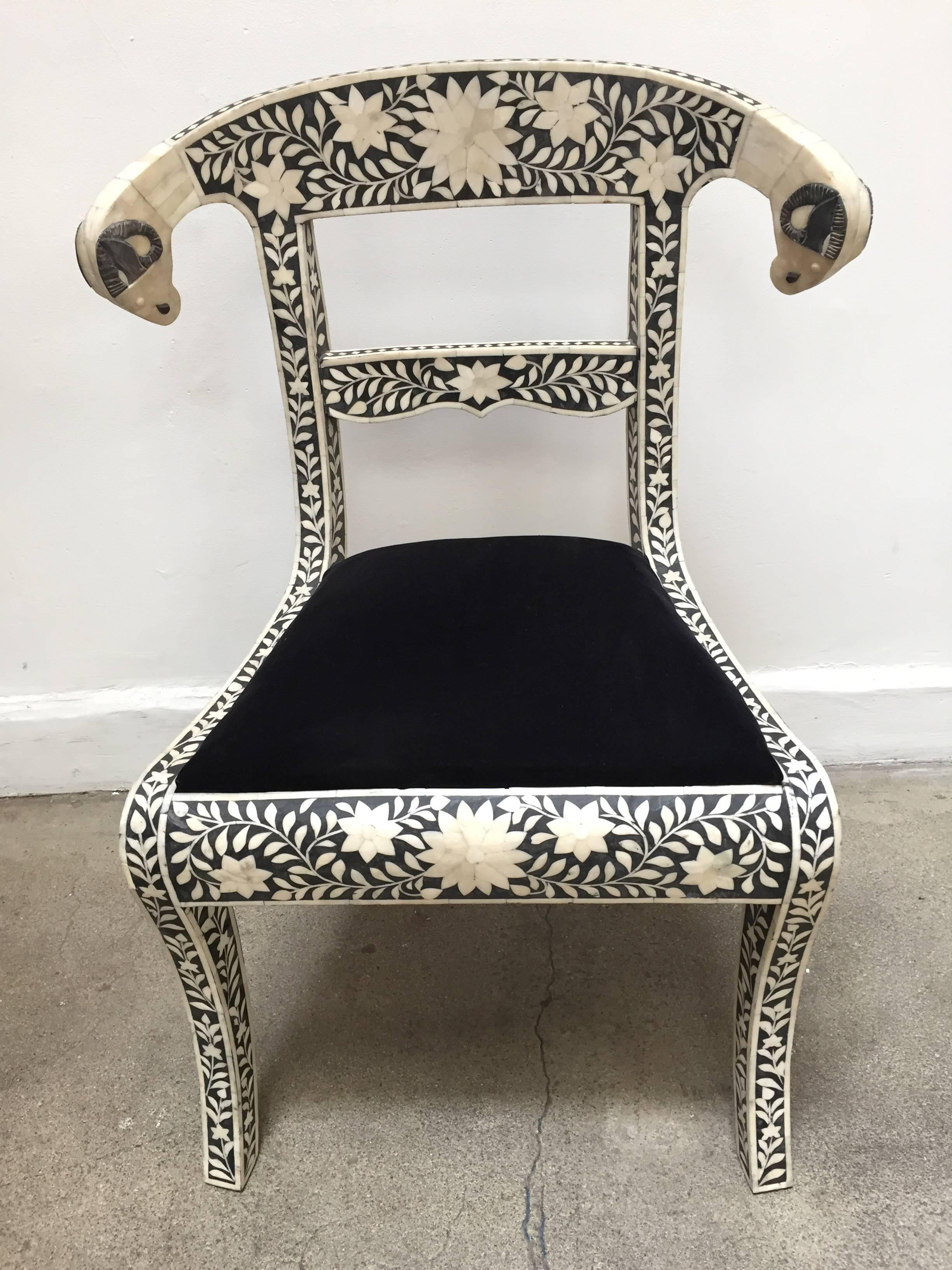 Pair of Anglo-Indian Mughal black and white dowry side chairs with ram's head accents.
These stunning chairs feature a wooden frame inlaid with intricate and detailed floral bone inlay design in ivory and black color and scrolling ram's heads