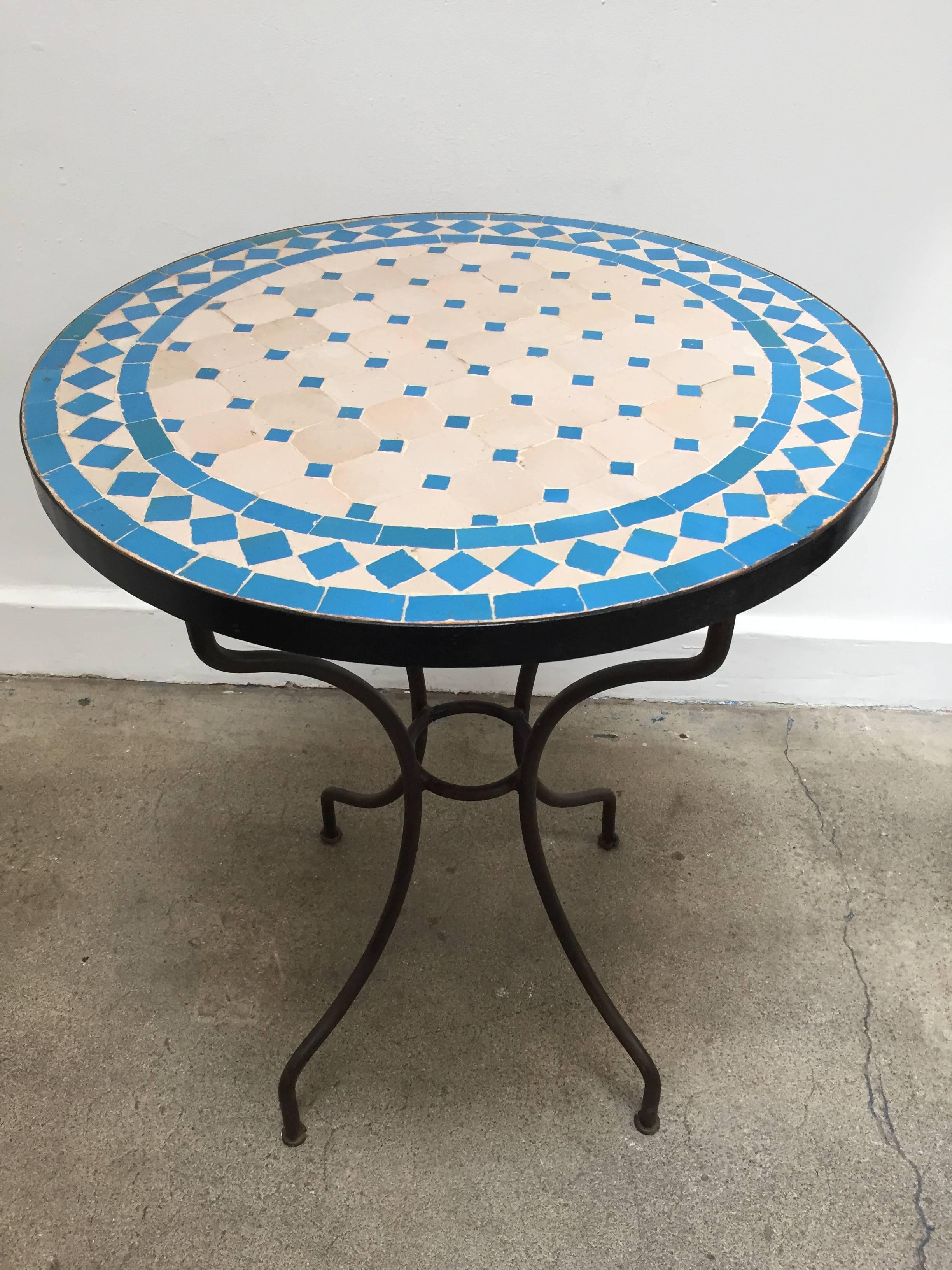 Moroccan mosaic tile bistro table on iron base. 
Handmade by expert artisans in Fez, Morocco using reclaimed old glazed blue and tan tiles inlaid in concrete using reclaimed old glazed tiles and making beautiful geometrical designs, colors are