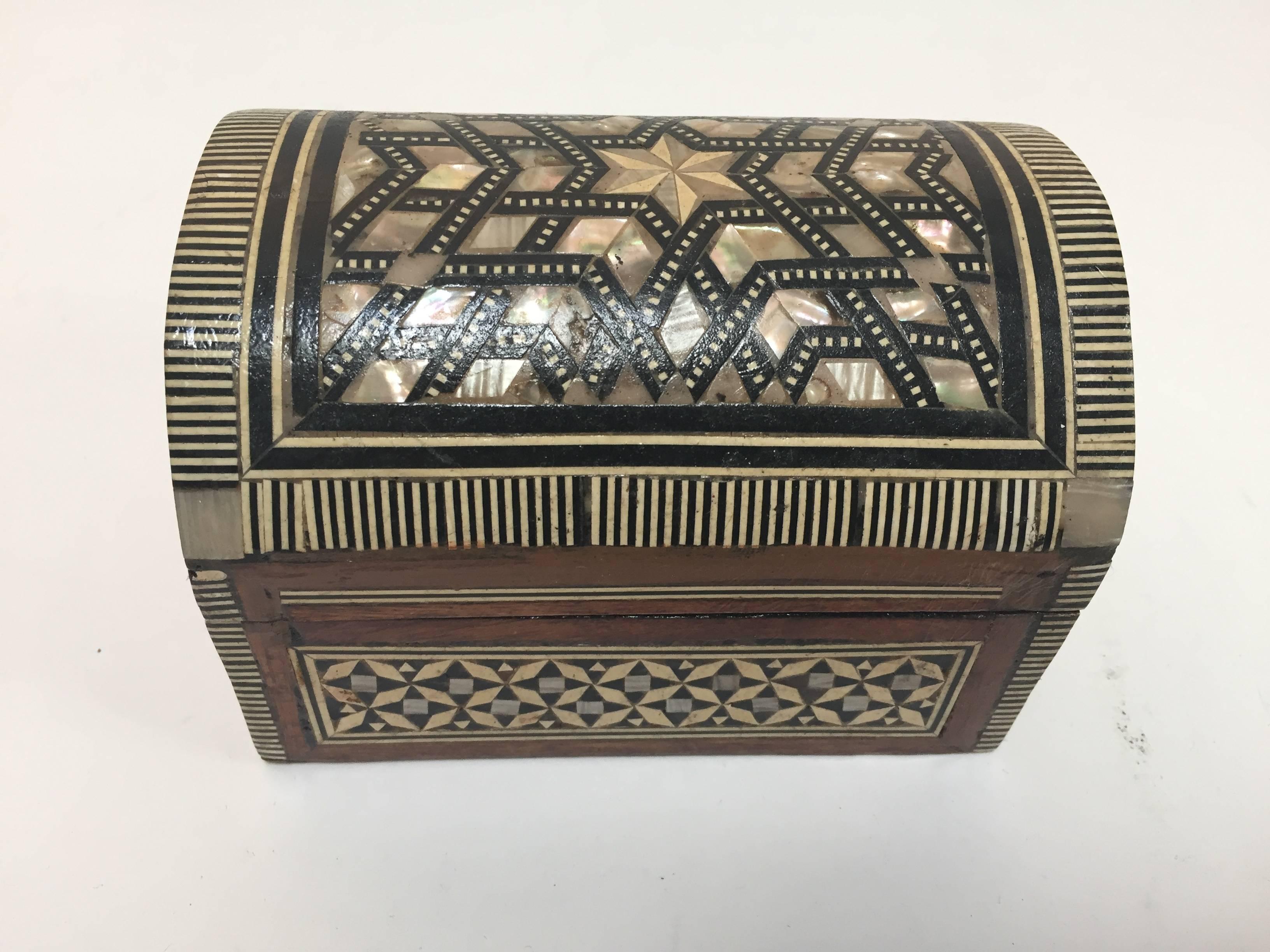 Exquisite handcrafted Middle Eastern Syrian mother-of-pearl inlaid walnut wood jewelry box.
Small dome chest intricately decorated with Moorish motif designs which have been painstakingly inlaid with mother-of-pearl and marquetry in different