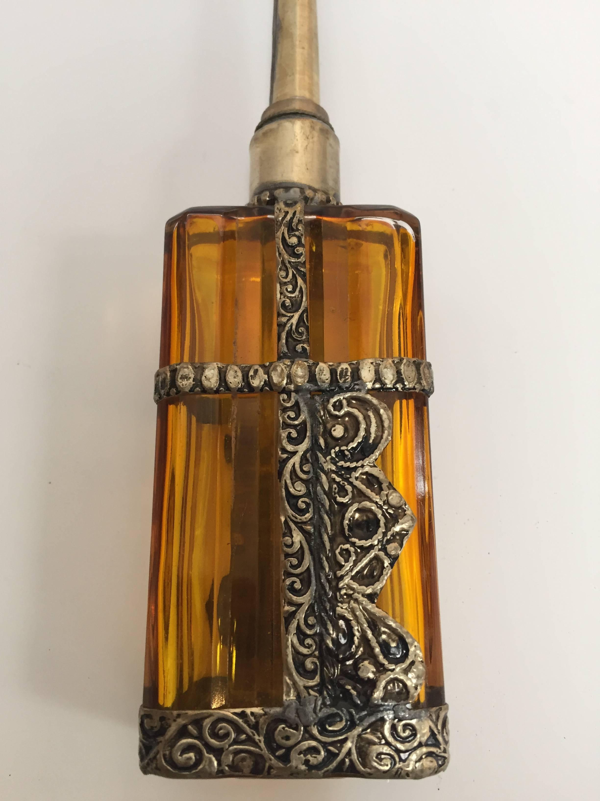 Handcrafted Moroccan glass perfume bottle or rose water sprinkler with raised embossed silvered metal floral design over amber glass.
The pressed glass bottle in Art Deco, Art Nouveau style is in rectangular shape and hand decorated with embossed