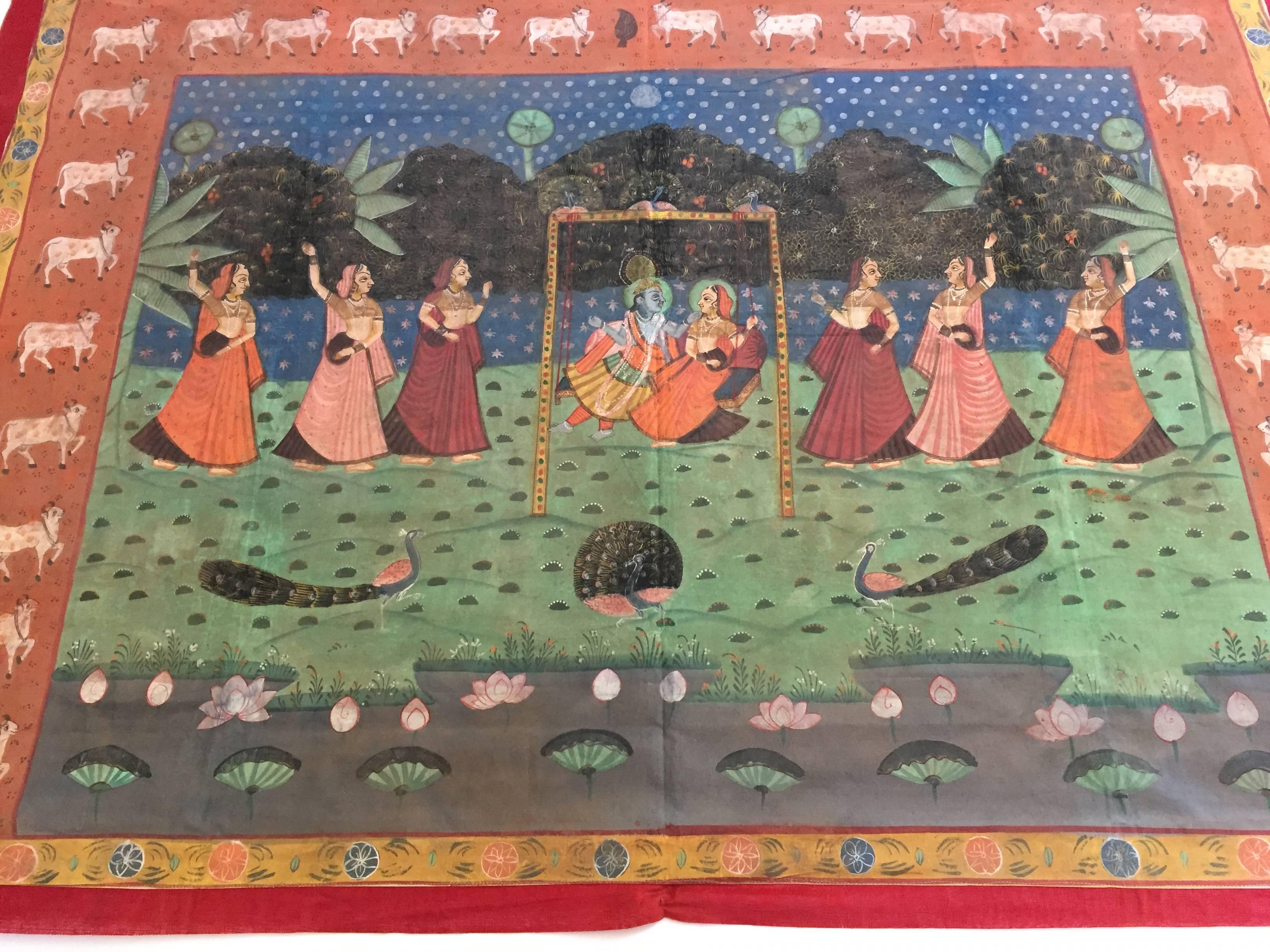 A large Pichhavai painting depicting Krishna playing on a swing with a beautiful lady with female Gopis dancing and offering around them, great colors, the composition is enclosed in a lush green forest and the colors of the dresses in oranges play
