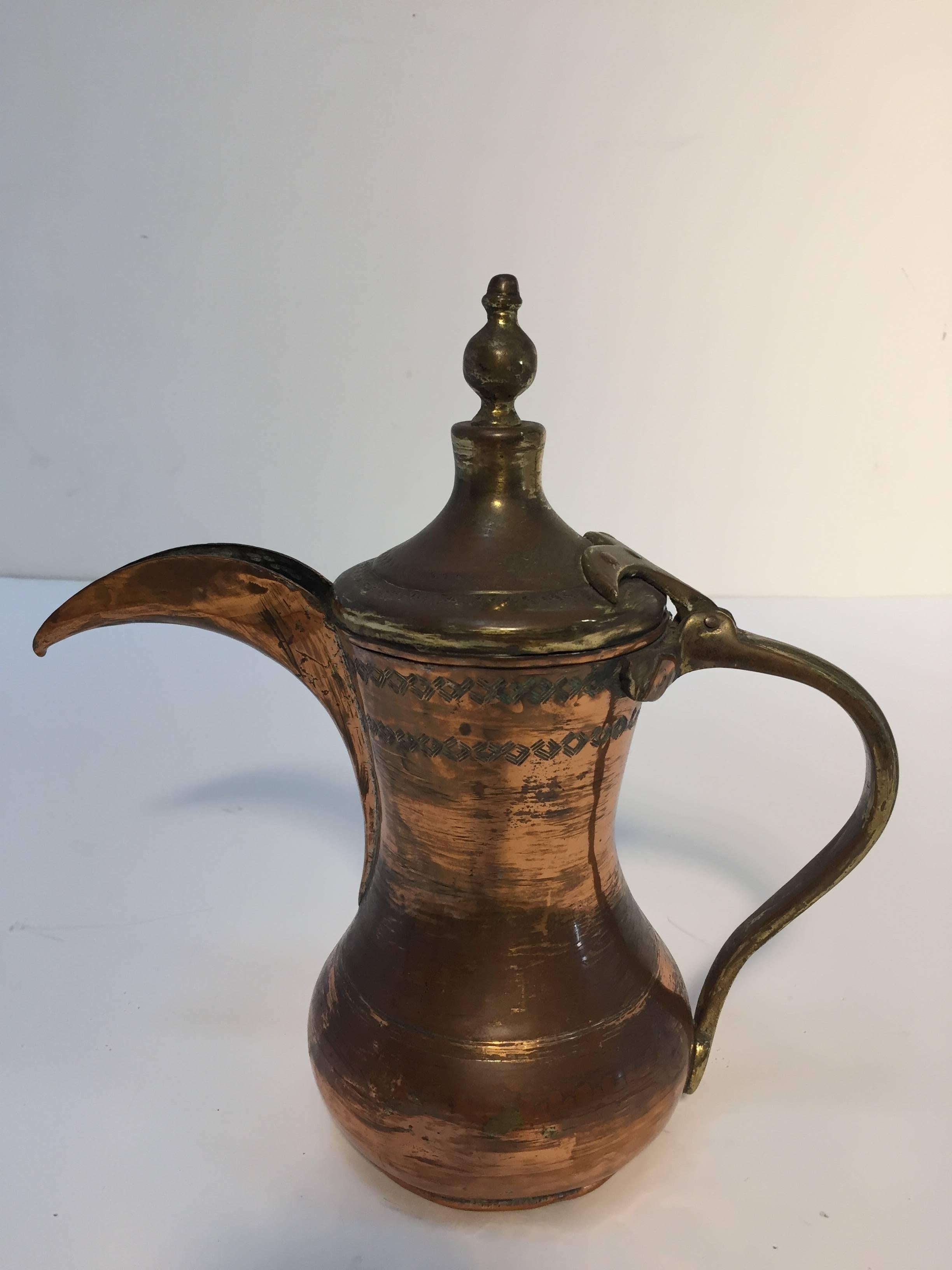 19th century Middle Eastern Arabian tinned copper Dallah coffee pot.
Antique decorative Arabic coffee pot hand-hammered and chased copper with riveted brass finish. 
Probably from Oman. Moorish tribal design on top.
Size: 12